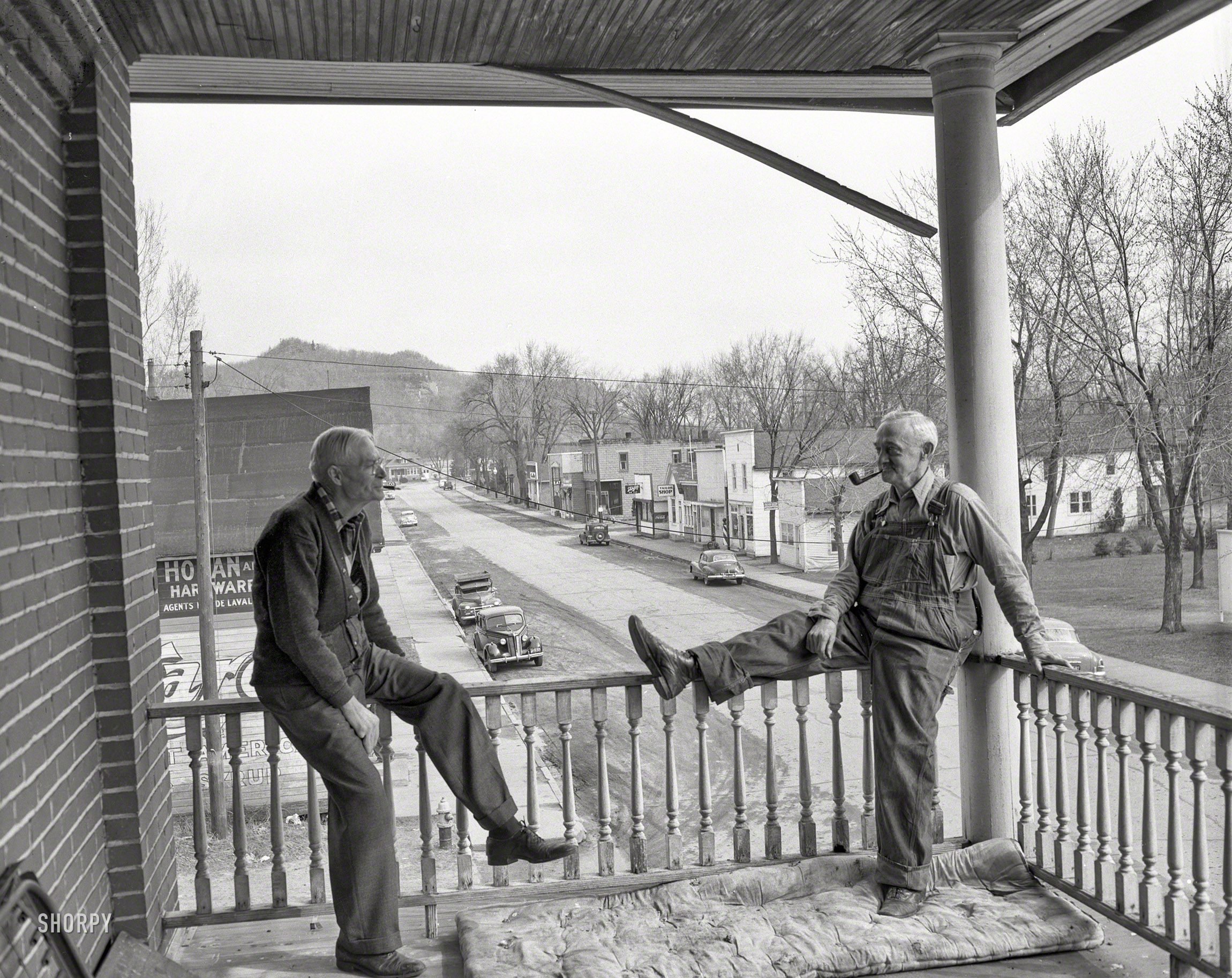 &nbsp; &nbsp; &nbsp; &nbsp; UPDATE: Main Street in Friendship, Wisconsin, at the Friendship Hotel, is the answer, supplied by "lifelong Wisconsin resident" Wiscojim. Clapclapclap!
Who can tell us where these old-timers are, other than on a porch near a mountain? 4x5 negative from the News Archive. View full size.