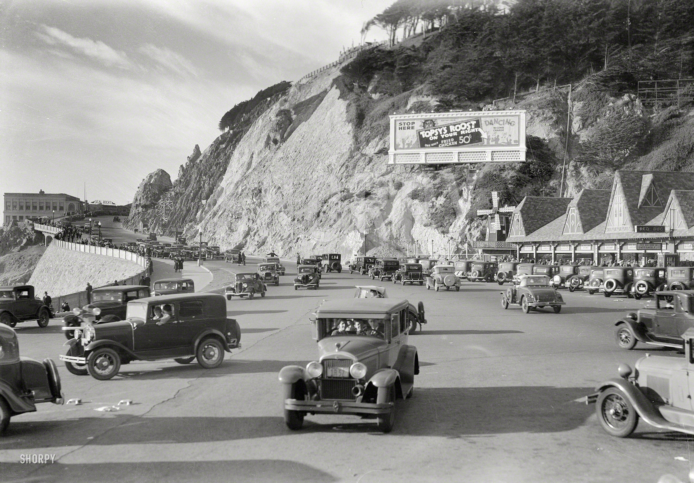 An interesting look at San Francisco car culture circa 1934. "Ocean Beach Playland -- Red Bug and Cliff House on Great Highway." With a billboard advertising Topsy's Roost, a dancehall and fried-chicken emporium just out of frame to the right. 5x7 negative, formerly of the Wyland Stanley collection. View full size.