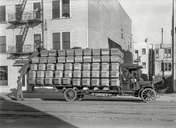 1918. "Federal truck -- San Francisco Casket Co." Makers of the box you'll go in. A sobering scene from the depths of the Spanish Flu epidemic. 5x7 inch glass negative by Christopher Helin. View full size.
Covid19 is a pandemic ... not a &quot;pandemic&quot;First of all, mwelch, May 2020 was way early in the pandemic to be taking a poll that you still consider to be valid in March 2022.  Just in the United States, nearly a million people have died from Covid19.  I probably didn't know anyone who had it in March 2020 either.  But today a [unvaccinated] neighbor across the street is dead from it and the brothers of three friends are dead. One friend said her brother's wife and children refused to wear masks at the funeral because "Covid is a hoax". As Dave, I know at least a dozen people, including family and immediate neighbors, who have had Covid.  It includes a couple in their 80s who, for some reason decided flying to Chicago was more important than avoiding exposure.  The husband spent two months in the hospital after they got back and came home with an oxygen tank.  I know two people who suffer from serious long-term effects of Covid; one wakes up with a hangover every morning and cannot concentrate for more than a few minutes at a time.
I'll also point out that asking random people in a line about a potentially deadly disease for which there was no treatment is a really bad approach to collecting information about the disease.  I imagine some people told you, "No" because they didn't want to answer the follow-up question to a "Yes" answer.  It was also a really rude question to be asking strangers.
Comfort?Look at that truck's suspension and talk about a hard ride. 
Not that one would care in the first place. On one's final ride. 
Mass TransitNot the most luxurious of hearses, but isn't it commodious, though?
A simple pine box?The wood used in these caskets appear to be redwood or cedar likely shipped down the coast from Northern California or Seattle. In 1900 a typical casket was made of wood often covered in cloth. Costs were around $16, about $400 in today's dollars. Mass-produced steel caskets didn't show up until 1918 when Batesville Casket introduced them. These appear to be a bit fancy with all the molding, 3 or 4 different styles. Curious what the numbers stamped on the ends indicate.
Dept. of Public HealthNOTICE -- something about GARBAGE, MANURE, REFUSE and "premises."
They Opened the Door and In Flew EnzaPerhaps the 1918 date is not a coincidence. The worldwide outbreak of Spanish Influenza  in 1918 killed more people than WWI, and while San Francisco  was spared the worst of it, there were still over 40,000 ill and 3000 dead in the city during the later half of 1918.
Considering it killed a disproportionate number of the poor and recent immigrants, a truckload of obviously low end (judging from the unfinished wood and lack of decoration or hardware) would have been a common sight for a few months.
OverloadedConsidering there are no brakes on the front and probably mechanical ones on the rear, I sure wouldn't want to try to stop that overloaded truck on a San Francisco Hill!
It looks like a scene from a comedy short, where the front of the truck suddenly flies up when they try to start.
CoffinThe two top rows are caskets.  The bottom three are coffins I believe.
More Than Just NumbersIf you increase the resolution size of the photo you will see scenic views either hand painted scenes, lithographs or photos on the ends of the caskets, not numbers.
[Amazing. I see "The Last Supper" and "Dogs Playing Poker." What do you see? - Dave]

In the high-res blowupIn the lower board of the upper casket, I see a group of well-dressed office workers, circa 1925, at some sort of holiday gathering. One woman has an oil can in front of her.
I never would have noticed that without seeing this high-res enlargement. The lower casket just has a typical beach scene in what appears, to me, to be Galveston, Texas. Two people are walking, two are riding horses.
Coffins vs CasketsCoffins are where Vampires sleep, Caskets are what they bury dead people in.
Pareidolia&nbsp; &nbsp; &nbsp; &nbsp; A psychological phenomenon involving a stimulus (an image or a sound) wherein the mind perceives a familiar pattern of something where none actually exists.
&nbsp; &nbsp; &nbsp; &nbsp; Common examples are perceived images of animals, faces, or objects in cloud formations.
&nbsp; &nbsp; &nbsp; &nbsp; Pareidolia is the visual or auditory form of apophenia, which is the perception of patterns within random data. Combined with apophenia and hierophany (manifestation of the sacred), pareidolia may have helped ancient Chinese society organize chaos and make the world intelligible. -- Wikipedia
[That would explain it. - Dave]
How to explain Shorpy.com?!?!??!A couple of weeks ago I was talking to some Kaiser Permanente associates from the California region. Killing time until all the folks were on the line, I asked where they were calling from, and they said,"Oakland." I laughed and said, "I hope you drive better than some of the long-ago Oakland drivers I've seen on Shorpy.com."
"What's that?" they asked.
"Well, it's mainly a large-format photography site, but the whimsical subject matter and amazing comments of the moderators and readers are what make it a Web addiction. Like the Oakland drivers; for the past couple of months they've had a series of 1950s photos of Oakland traffic accidents. And they have kittens dressed as people and beach scenes from 100 years ago, and . . . and decrepit old buildings . . . and . . . and there are photos of . . ."
"Jim, this is another one of your wild stories, right? There's no such thing as Shorpy.com, right?"
-------------------------------------------------------
Imagine if I tried explaining it today, with people seeing imagery in the woodgrain of caskets from 100 years ago!
The San Francisco Casket CompanyThe sign in the front window indicates this photo was taken in front of the headquarters for the San Francisco Casket Company, Inc. (SFCCI) which was at 621 - 627 Guerrero in 1918.
The firm was started about 1900 by George Dillman, and it was originally located at 542 Brannan.  Dillman had been working at Samuel Nelson &amp; Co., who were casket manufacturers, immediately before this.  About 1903, SFCCI moved to 3120 17th Street for approximately two years, and then to 17th and Shotwell until around 1908.  John H. Nuttman (1856 - 1946), who had been the vice-president, became president around 1907.  It was circa 1908 that the business address changed to the 627 Guerrero location.     
The October 9, 1918 issue of Building and Engineering News tell us this building on Guerrero was partially destroyed by fire causing $75,000 worth of damage.  With the ongoing influenza epidemic in the fall of 1918 the fire could probably not have come at a worse time for the firm.  The company had suffered another fire in February 1917 causing $15,000 in destruction to the four story structure.
The SFCCI then built a four story and basement brick factory, along with offices and showrooms, at 14th and Valencia for $75,000.  The brick work apparently cost $20,800, and the steam boiler system was $3,479.  The new factory address is shown as 325 Valencia in the 1919 Crocker-Langley San Francisco Directory, but later it became 321 Valencia.  
The building plans, by Etienne A. Garin, were completed in December 1918, White &amp; Gloor's plans for the building brick work were accepted on February 24, 1919, and all construction was completed by April 17, 1919.   The building was officially recorded by the city on July 7, 1919.  One interesting change is that Garin designed a mill work building, but architect Charles O. Clausen redesigned the plans to be reinforced concrete before the structure was built.
The new "L" shaped building still exists, but it has been heavily modified into residences and businesses.  Most of the original brick work has been hidden, but some is still visible down an alley way.  The company remained at this new location until 1962, but then it seems to have gone out of existence.
Eventually the president of the company became one of Nuttman's son, John B. Nuttman (1880 - 1960), and finally a daughter Hannah F. Spammer (1895 - 1980). 
The snippet from Building &amp; Engineering News below is from October 16, 1918 which tells of the fire.  The second piece, from "The Standard," a weekly insurance newspaper from May 17, 1919, relates how the rules of the San Francisco Fire Commission prevented a quick extinguishing of the 1918 blaze.  The last article, from the October 20, 1910 San Francisco Call, describes how one of the SFCCI drivers got out of a speeding ticket.  The driver is likely William I. Nuttman (1889 - 1973) another one of John H. Nuttman's sons.
A tisket, a tasketAll I know is, a coffin is a box with a separate lid that has to be nailed on; hence the expression, nail in your coffin. A casket is a piece of furniture with hinges and handles and padding and a pillow and whatnot. What can I say? I am a bona fide taphophile with thousands of funeral and cemetery photos (taken by me) to prove it, and I have an intense interest in end-of-life issues. Moving along, I cannot explain it but this wonderful photo of fifty wooden coffins/caskets stacked sky-high instantly reminded me of one of the funniest black-humor scenes I have ever seen on television. It was from the Bruce Willis slash Cybill Shepherd farce, Moonlighting, which aired back in the '80s. As I remember it, they (BW and CS) were driving a hearse in a high-speed chase and somehow they ended up smack dab in the middle of a baseball diamond, stopping the hearse so abruptly that the casket flew out of the back and came to rest on home base where naturally the body slid out, whereupon the umpire loudly pronounced him safe, eliciting markedly unladylike and protracted guffaws from me.
Truss but verifyI don't think I've ever seen truss rods on a truck before.  They were still fairly common on rail cars - tho rapidly becoming obsolete - but those, of course, are typically a lot longer than a truck.
(A quick search will turn up a like-bodied family member https://www.shorpy.com/node/18816  ...perhaps this something peculiar to the 'Federal' make)
Stacks and Stacksof coffins. An older friend of mine, who was a child at the time, attested to the severity of the flu epidemic. He well remembered coffins stacked 5 high and in several rows in the parking lot alongside an undertaking establishment here. No room inside, of course. 
In 1918 people knewAbsence of a visual like this made me question the current "pandemic". I had initiated an inquiry in long Covid-lines, ending with cashier or a bank teller.
Not a single case, in their family, circle of friends and friends of a friends "had it".
I am talking as early as of May of 2020.
[Covid-19 is not even half as deadly as the 1918 Spanish flu. On the other hand, there are thousands of "visuals like this." Personally I know around a dozen people who've "had it," including family members. - Dave]

Pandemic MemoriesI remember Mom saying "they couldn't make coffins fast enough." She was born in 1908.
Why it&#039;s The USA@mwelch, really enraging comment but I guess it's OK because my father fought in WWII and was wounded to the day he passed at 90yrs old so you can speak. I guess you had no loved ones you couldn't be with as they died alone from covid. Grow up.
Eat, drink and be merryCovid has driven that home, at least a little. Remember, the last shirt does not have any pockets. But it is also available in 5XL. 
Picking nits, the Spanish flu should rightfully be called the Kansas flu. That's where it reportedly first popped up. Then neutral Spain was just the first country where it was being officially reported from. With the US and much of the rest of Europe being under wartime censorship and the censors not wanting to hamper their respective war efforts by reports about a pandemic.  
I second Doug Floor Plan about COVID supposedly just being a glorified cold - not. 1918-1920 they did not have the medical knowledge we have. Or the medical means. Or our general health and wealth. We do not have the starved-out war-worn population they had after WWI. Send COVID back to 1918, and presto, it would do the Spanish flu thing in no time flat. 
Just think - no masks, no shutdowns, no remote schooling, no home office, no vaccines, no tests, no quarantine, no oxygen supplements, no anitbiotics against opportunistic pneumonia, no ICUs, no ECMO, no antithrombics, no nothing. Under 1918-1920 conditions Covid would do the Spanish flu thing in 2020-2022 all right. 
A &quot;rude&quot; question for doug floor plan.  You seriously believe a "pandemic" with a survival rate of %98.6 is comparable to the spanish flu of '18?    The BS you spewed about family and friends dropping like flies tells me ALL your dead friends and family were morbidly obese and or elderly.  Also, that 1 MILLION covid deaths is also BS.   People who believe MSM propaganda are useful idiots, nothing more.  Appreciate ya outting yourself. 
[I was going to say something here but golly, it looks like I'm due back on Planet Earth for this week's MSM Conspiracy Workshop! - Dave]
Hey, folksIt’s depressing to see this covid scrap break out under the coffin photo, but I suppose it had to happen sooner or later.  There is plenty of room for discussion about the measures and responses (It’s a social, political, and ethical discussion), but there’s really no room to question whether it actually happened.  My family of six is double-vaxxed but we all got omicron over the holidays, ranging from nasty aches and pains to a runny nose for davidk, the oldest of the bunch.  No one went to the hospital, no one died, but we all tested positive on the home test kit.  After the passage of a few months, we then all got the booster shot.  Please let’s not pretend this isn’t a thing.  And please let’s be civil and rational – this is a huge test for us as a community and as a society.
(The Gallery, Cars, Trucks, Buses, Chris Helin, San Francisco)