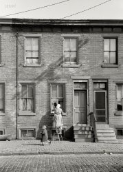 October 1938. "Factory workers' homes in Camden, New Jersey." 35mm negative by Arthur Rothstein for the Resettlement Administration. View full size.
Forget the windowsFix that rotting cornice! Neighbors are beginning to wonder when hubby is going to tackle that eyesore.
Workingman&#039;s HouseIn the Philadelphia Rowhouse Manual, this is labeled as a mid to late 19th century Workingman's House.  I would guess this example dates to no later than the 1880's based on the detailing.  As Camden is essentially a suburb of Philadelphia, this house probably follows the general type built in the Philadelphia area pretty closely.
PerfectThe horizontal bands of sky at top and curb/street at bottom, and the shadow of a utility pole on the building make this a very special image by one of the FSA's greats.
Where&#039;s the Windex?It appears that the lady of the house smeared the window cleaner on the window on the left but didn't wipe it off and then moved to the window on the right...so, not being a domestic engineer I'm wondering about the process.
[She's using a product like this. -tterrace]
Glass Wax?She might have been using Glass Wax, which my parents were using in the 1950s. It had the same effect. Leave a haze and wipe it off.
(The Gallery, Arthur Rothstein, Kids)