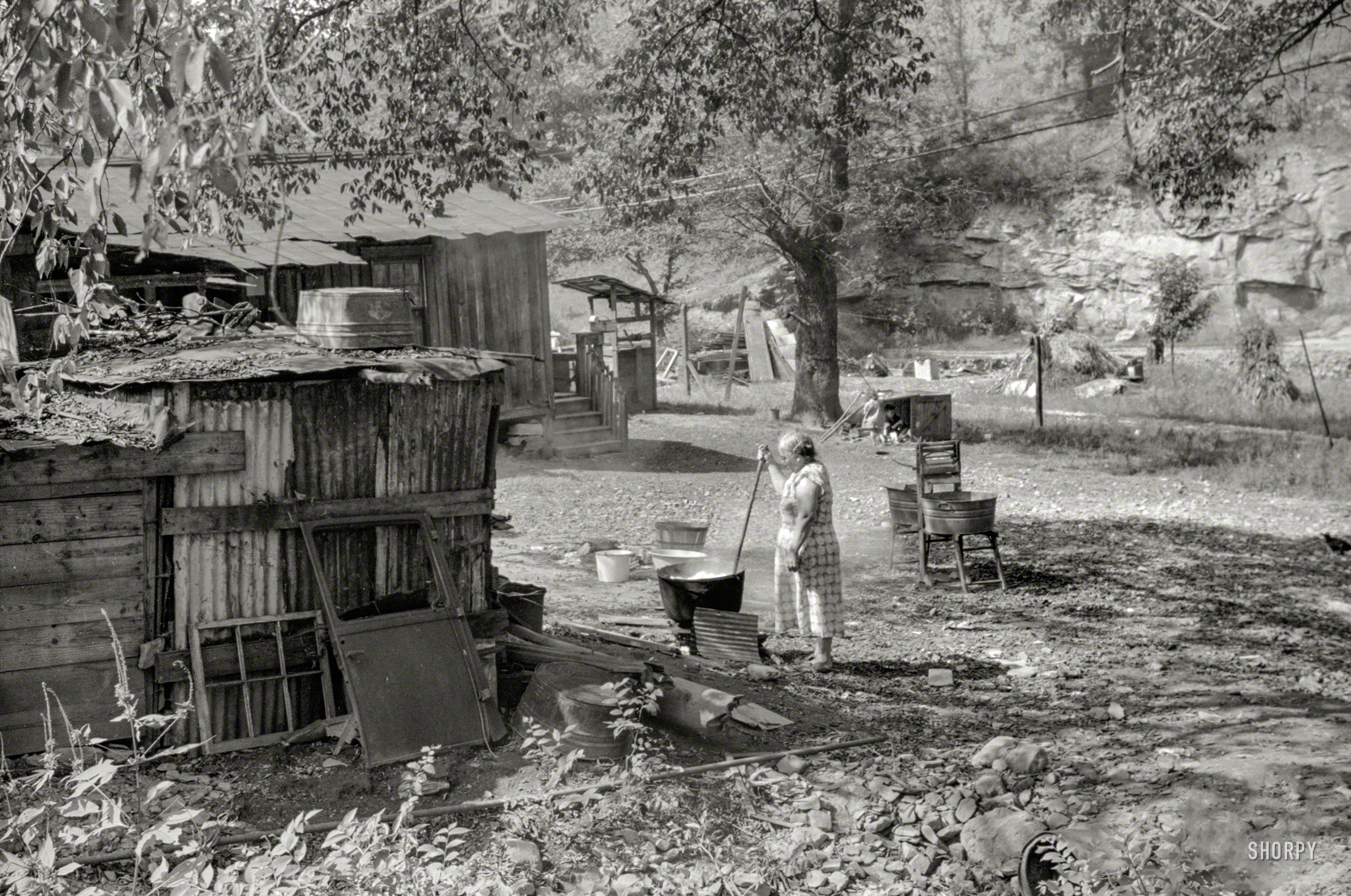 From September 1938, a reminder of the days when doing laundry meant hauling water from a well or spigot, then boiling it in a caldron over a fire: "Old and sick, mine foreman's wife does washing in front yard. South Charleston, W.Va." Photo by Marion Post Wolcott for the Resettlement Administration. View full size.
