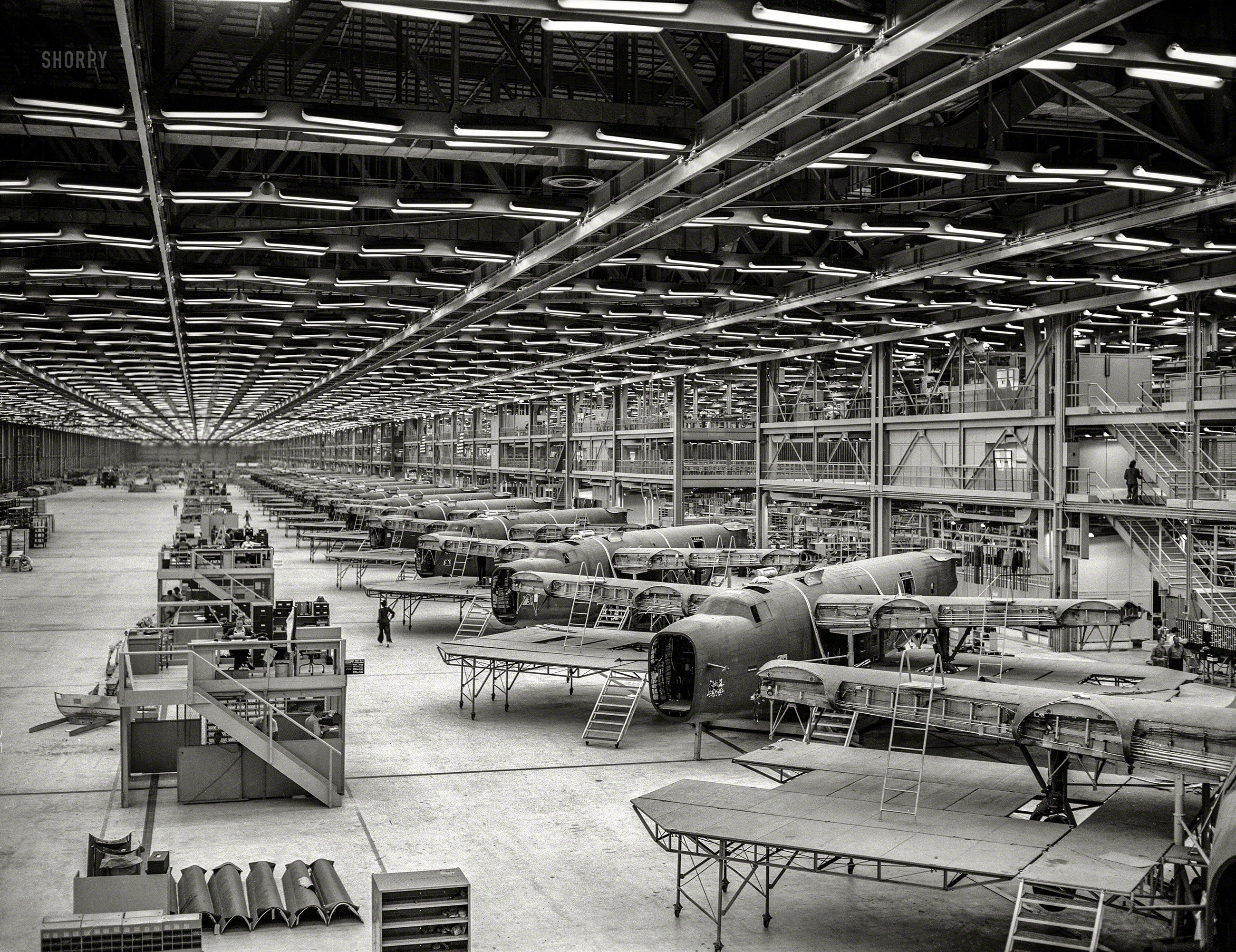 October 1942. The Consolidated Aircraft Corp. plant in Fort Worth, Texas. "Production. Halfway down the final line of a Western aircraft plant at which B-24 bombers and C-87 transports are made. This new transport, an adaptation of the B-24 bomber, is known as the C-87 and carries one of the greatest human or cargo loads of any plane now in mass production. It is built in a plant equipped with one of the best air conditioning and fluorescent lighting systems in the country." Photo by Howard Hollem for the Office of War Information. View full size.