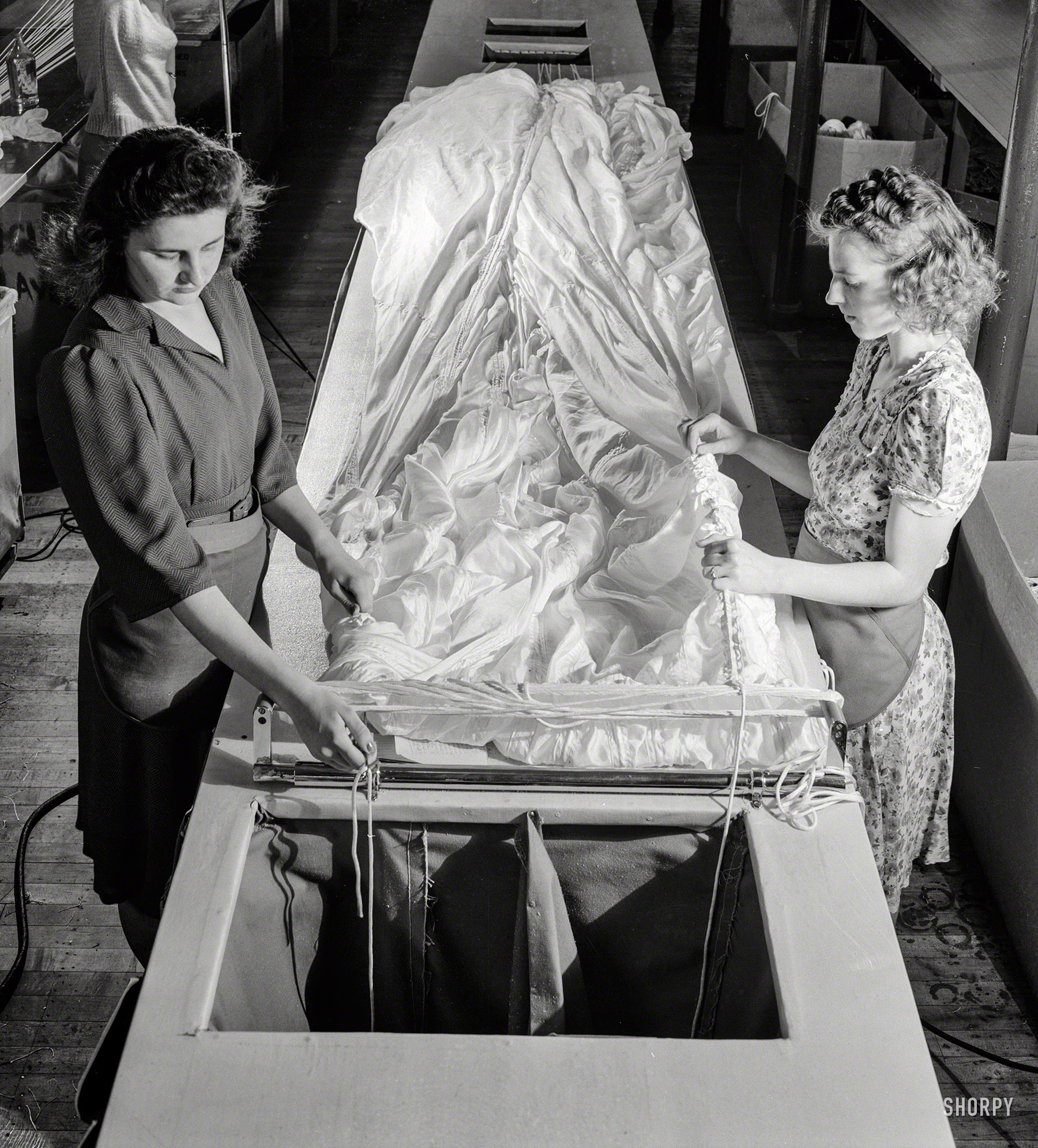 August 1942. "Production. Parachute making. As these two girls thread shroud cords through the material, these yards of silk become more nearly recognizable as one of the parachutes turned out by this Eastern plant. Pioneer Parachute Company, Manchester, Connecticut." Photo by William Rittase for the Office of War Information. View full size.