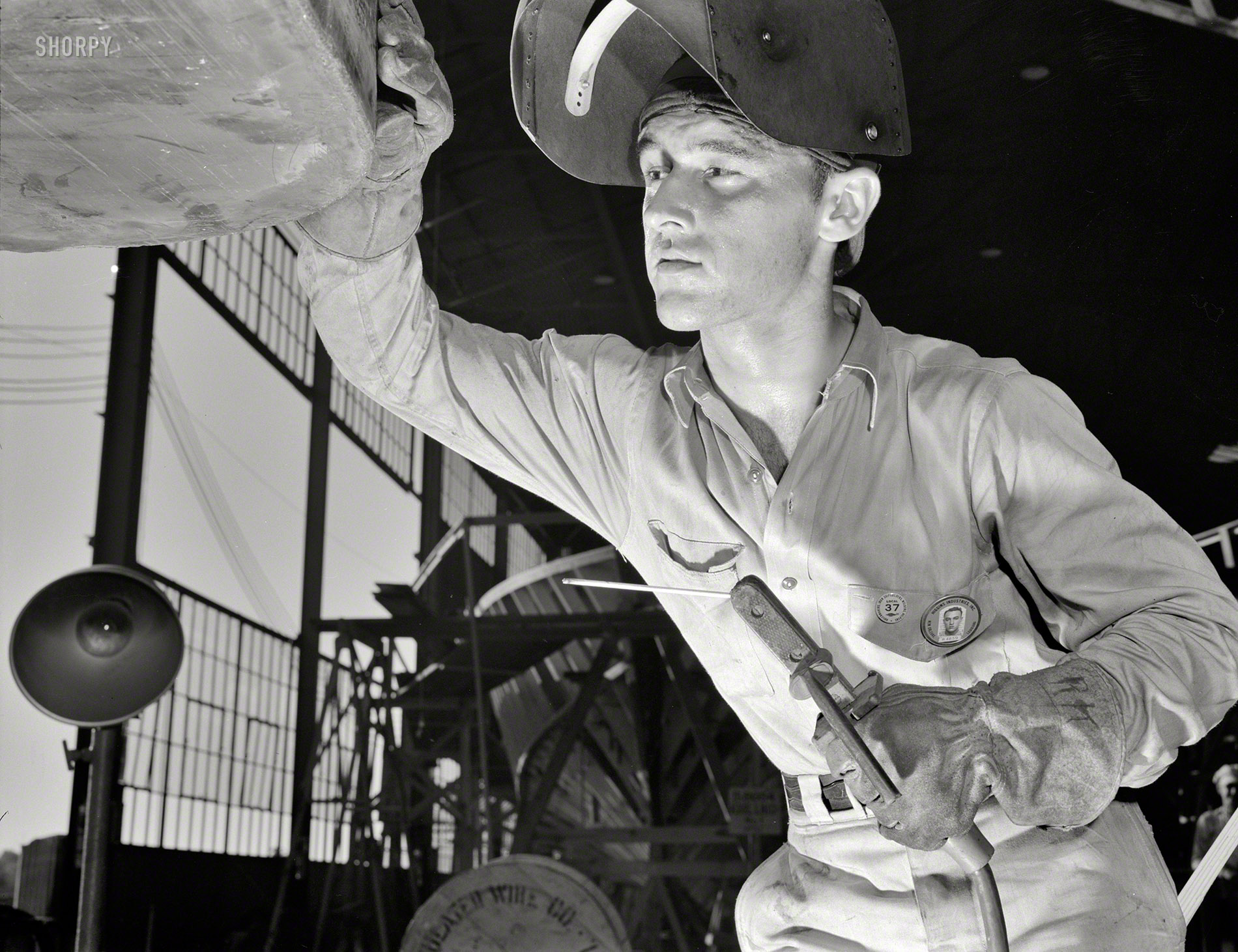 July 1942. "An electric arc welder at a large Southern boatyard examines a bead he has just run on a steel ramp boat which will be used in making beach landings of men, tanks, and other equipment on hostile shores. Higgins Industries, New Orleans." Photo by Howard Hollem, Office of War Information. View full size.