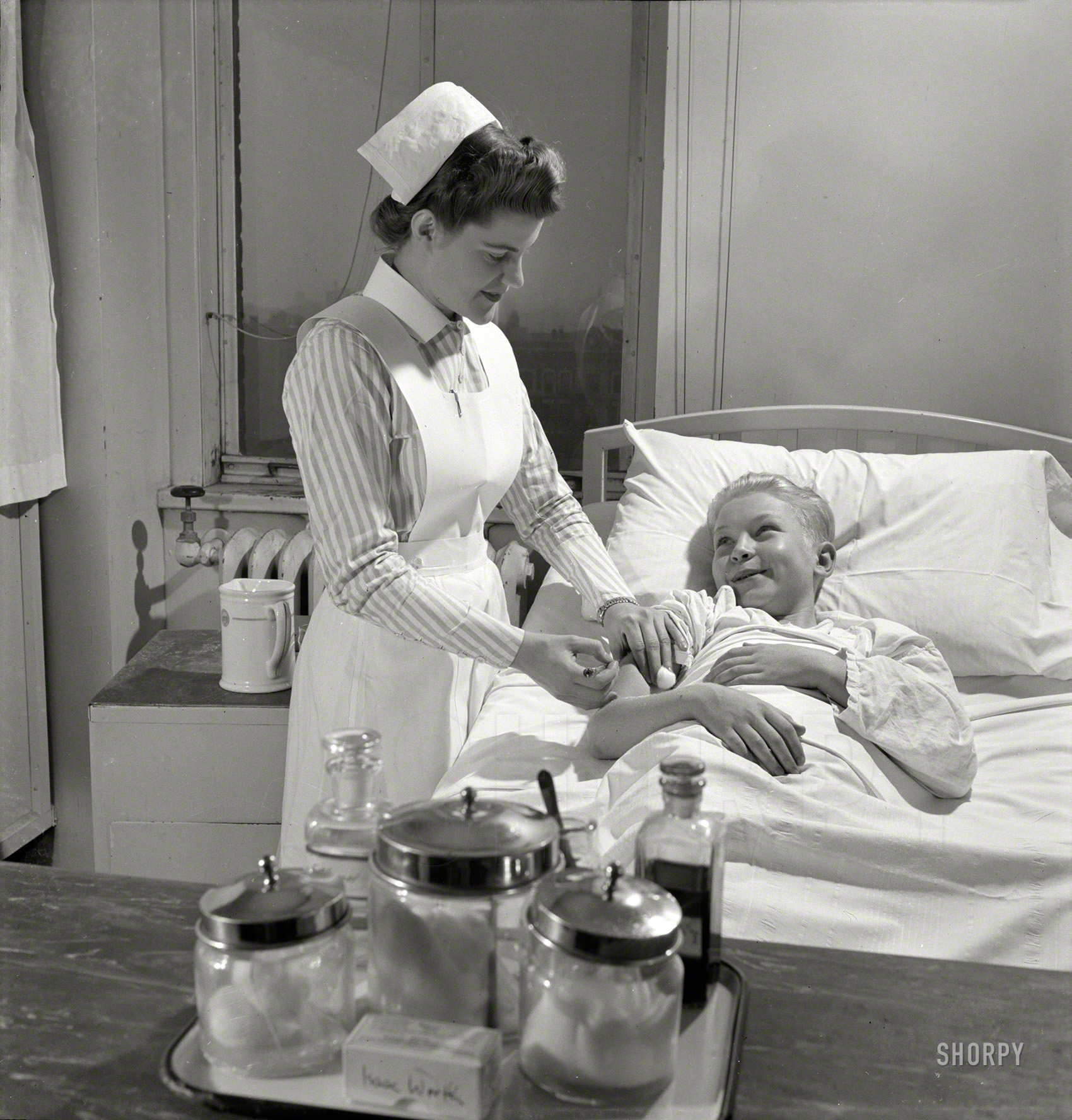 November 1942. "Nurse training at Babies' Hospital, New York. Student nurses, like Susan Petty of Lebanon, Pennsylvania, are rendering their country a great service by making it possible for experienced nurses to join the Army or Navy Nurse Corps. Relieved of such civilian duties as administering injections to patients like this smiling youngster, graduate nurses are tending America's fighting men in distant parts of the world." Medium format negative by Fritz Henle for the Office of War Information. View full size.