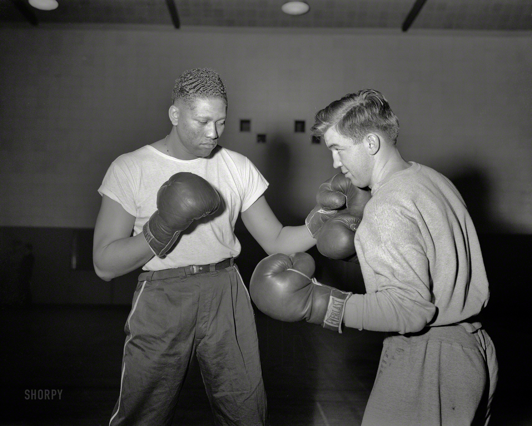 January 1943. "The gymnasium is one of the busiest places at the Manhattan Beach Coast Guard training station. The physical education program is handled by many noted exponents of boxing, wrestling, track and judo. Paul "Tiny" Wyatt, one-time leading contender for heavyweight boxing honors, is shown sparring with Herb Kroeten, former Golden Gloves champ." 4x5 nitrate negative by Roger Smith for the Office of War Information. View full size.