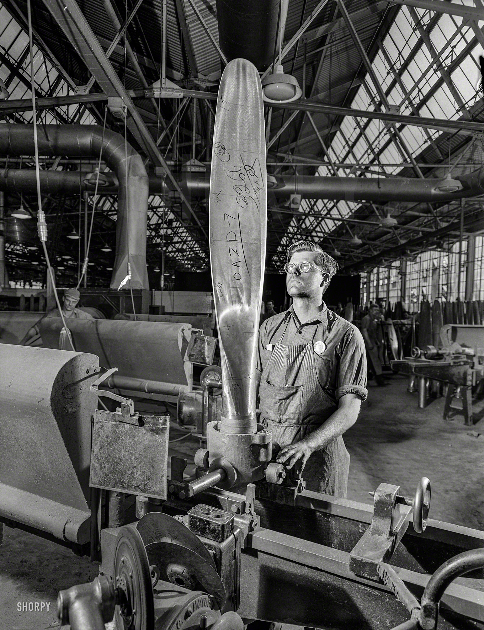 June 1942. "John Sonesen, propeller grinder at a Hartford, Connecticut, plant, inspects a blade for a vertical balance during the operation of grinding it to correct contours in a template. This Hamilton blade will be assembled in a pitch-controlling Hydra-Matic mechanism to help power one of our new warplanes." Photo by Andreas Feininger for the Office of War Information. View full size.
