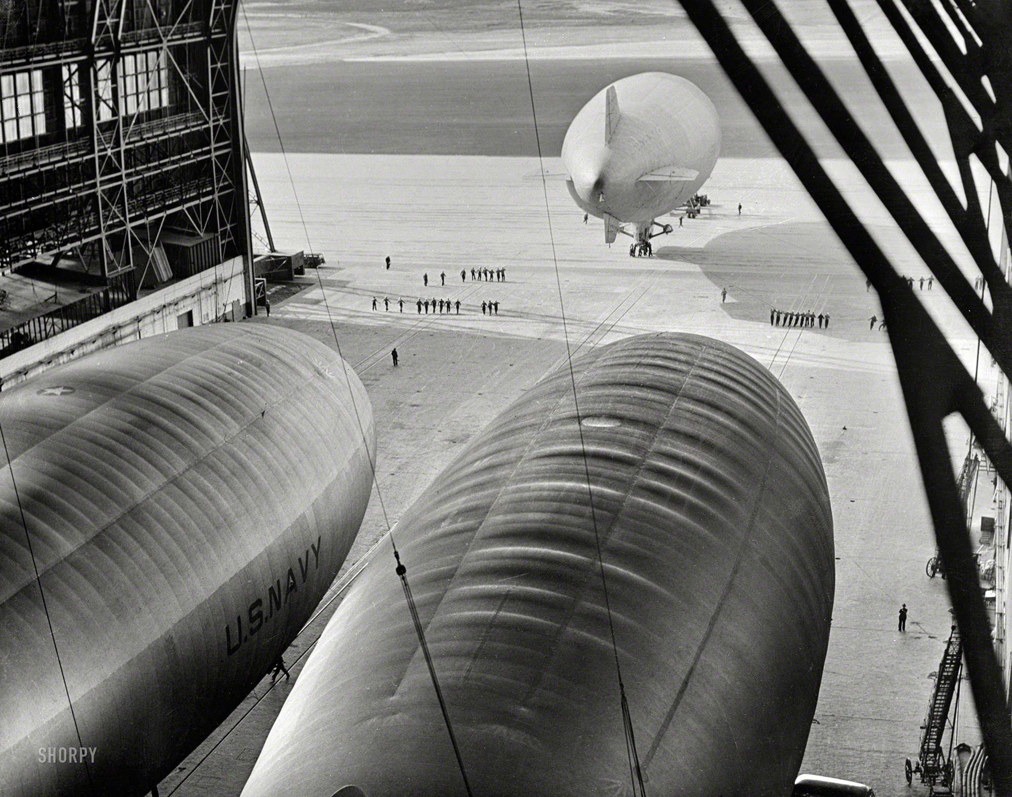 January 1943. "A blimp of the U.S. Navy is led onto the apron of an East Coast lighter-than-air station before taking off on a patrol flight over the Atlantic Ocean." 4x5 nitrate negative, Office of War Information. View full size.