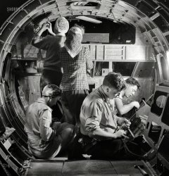 December 1942. "Production. B-17 heavy bomber. A skilled team of men and women workers at the Boeing plant in Seattle complete assembly and fitting operations on the interior of a fuselage section for a new B-17F (Flying Fortress) bomber. About half of the workers at the Boeing plant are women. The Flying Fortress has performed with great credit in the South Pacific, over Germany and elsewhere. It is a four-engine heavy bomber capable of flying high altitudes." Photo by Andreas Feininger for the Office of War Information. View full size.