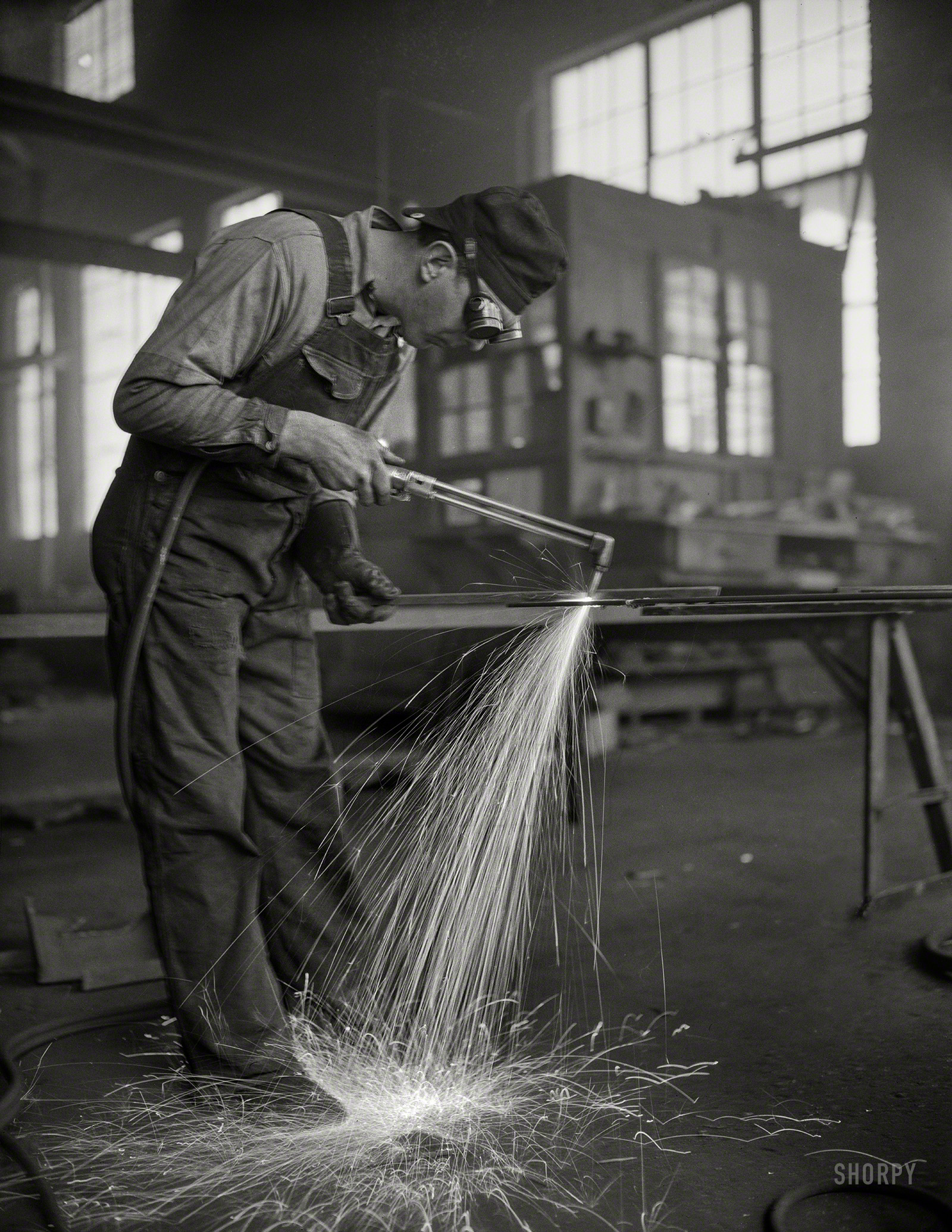 May 1942. "Twenty-four hours a day the sparks from acetylene torches of steel workers in eight Denver fabricating plants are flying thick and fast that the U.S. Navy may carry the battle to the enemy in all parts of the world. Here in secluded Denver, the world's largest city not on a navigable waterway, this war production worker, who has never seen a battleship or an ocean, fashions the steel hull parts which are being assembled at Mare Island Navy Yard in California -- 1,200 miles from where he and his fellow workers are on the job to help 'keep 'em sailing'." Office of War Information, photographer unknown. View full size.