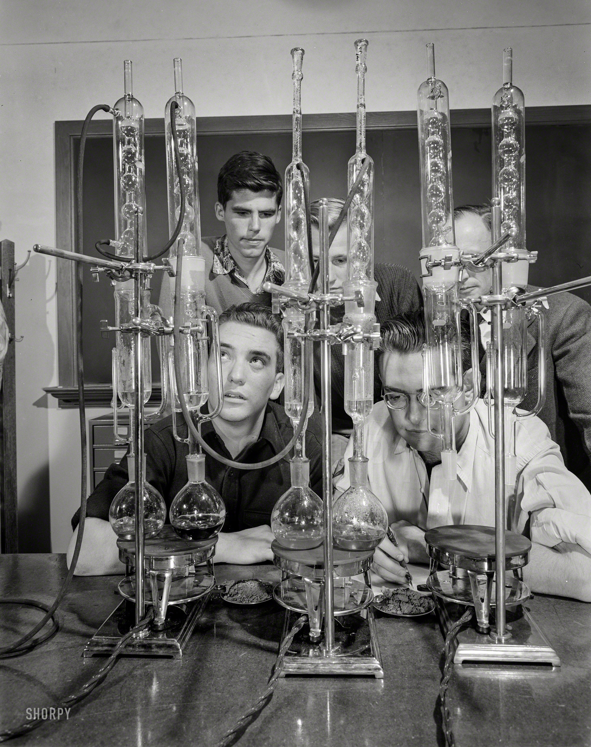October 1942. "Colorado School of Mines at Golden. Chemical prospecting for oil becomes more important as the war goes on and the demand for oil increases. Petroleum engineers call chemical prospecting the first scientific approach to the detection of oil in the earth. The big glass condensers, with which these engineering students are working with a professor of geophysics, are used in a soil analysis test. The percentage of wax left as residue at the end of the experiment indicates the nearness of petroleum to the site from which the soil sample was taken." Photo by Andreas Feininger, Office of War Information. View full size.