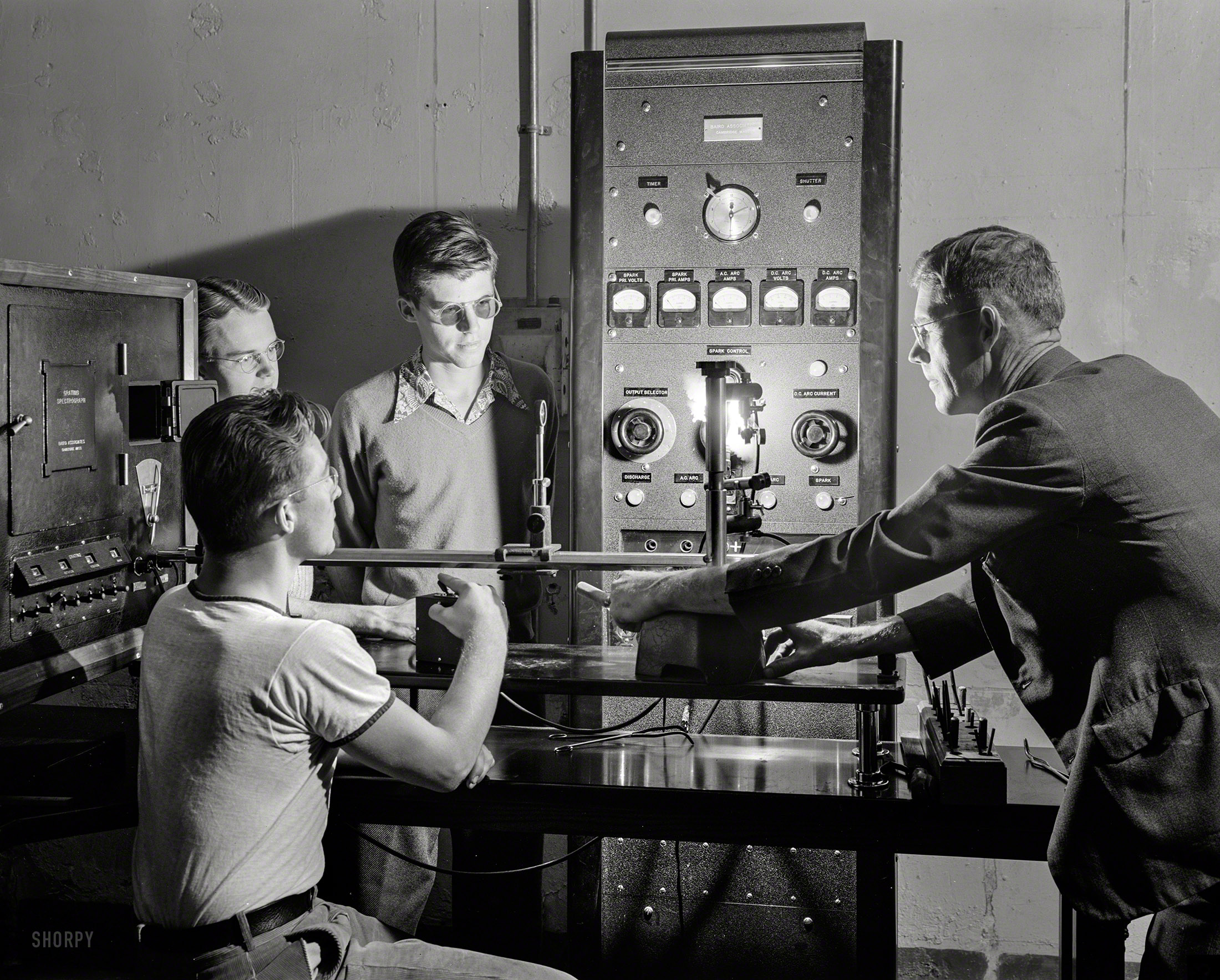 October 1942. State School of Mines in Golden, Colorado. "Speed in metallurgical anal&shy;ysis, to match the rapidity with which the nation arms itself, is possible through use of the spectrograph, a marvelous new machine used for study of materials through measurements of the arc of light they emit when heated. The aluminum and magnesium industries, steel companies and foundries use it for quick study of metals. Mines use it for exploration. The spectrograph will yield an analysis of seven elements in 15 minutes, which would require up to four hours by old chemical methods. Students in defense training courses at a famous mining-engineering school listen as an instructor shows them how the machine operates." Photo by Andreas Feininger, Office of War Information. View full size.