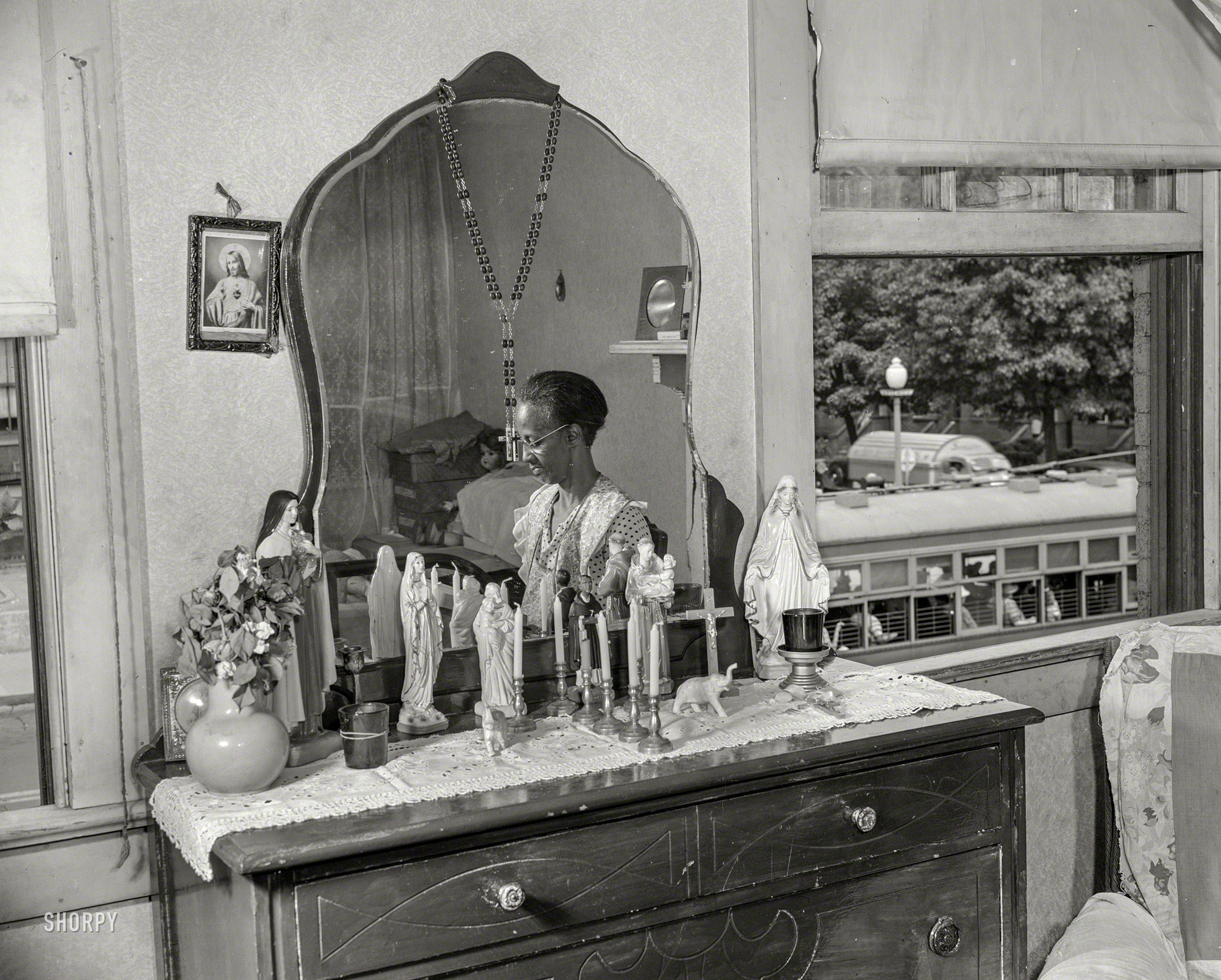 August 1942. "Mrs. Ella Watson, a government charwoman for 26 years who supports adopted daughter as well as daughter and three grandchildren on an annual salary of $1,080, reading the Bible in her bedroom." 4x5 inch acetate negative by Gordon Parks for the Office of War Information. View full size.