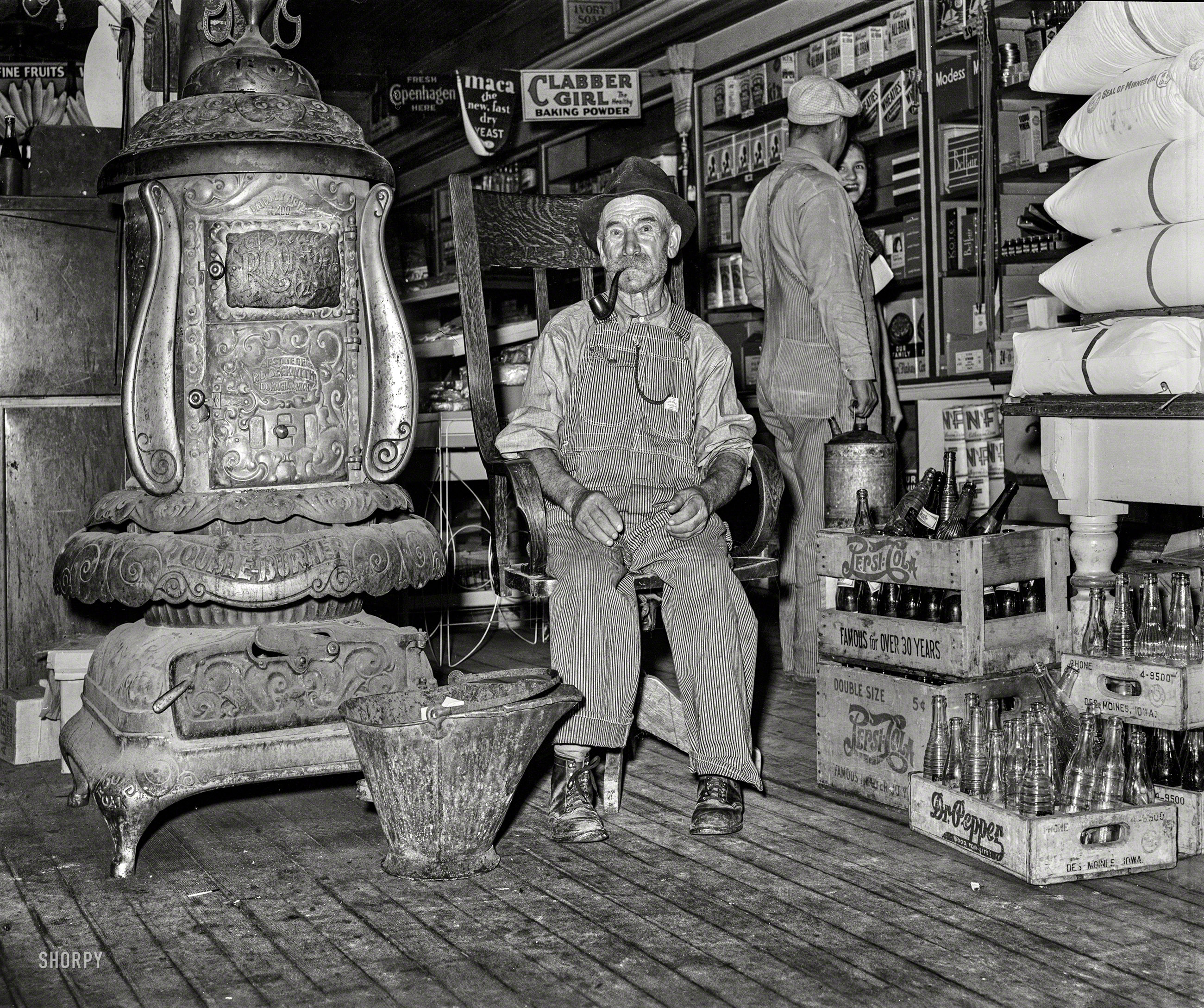 October 1939. "Farmer sits near the stove. General store in Lamoille, Iowa." Photo by Arthur Rothstein for the Farm Security Administration. View full size.