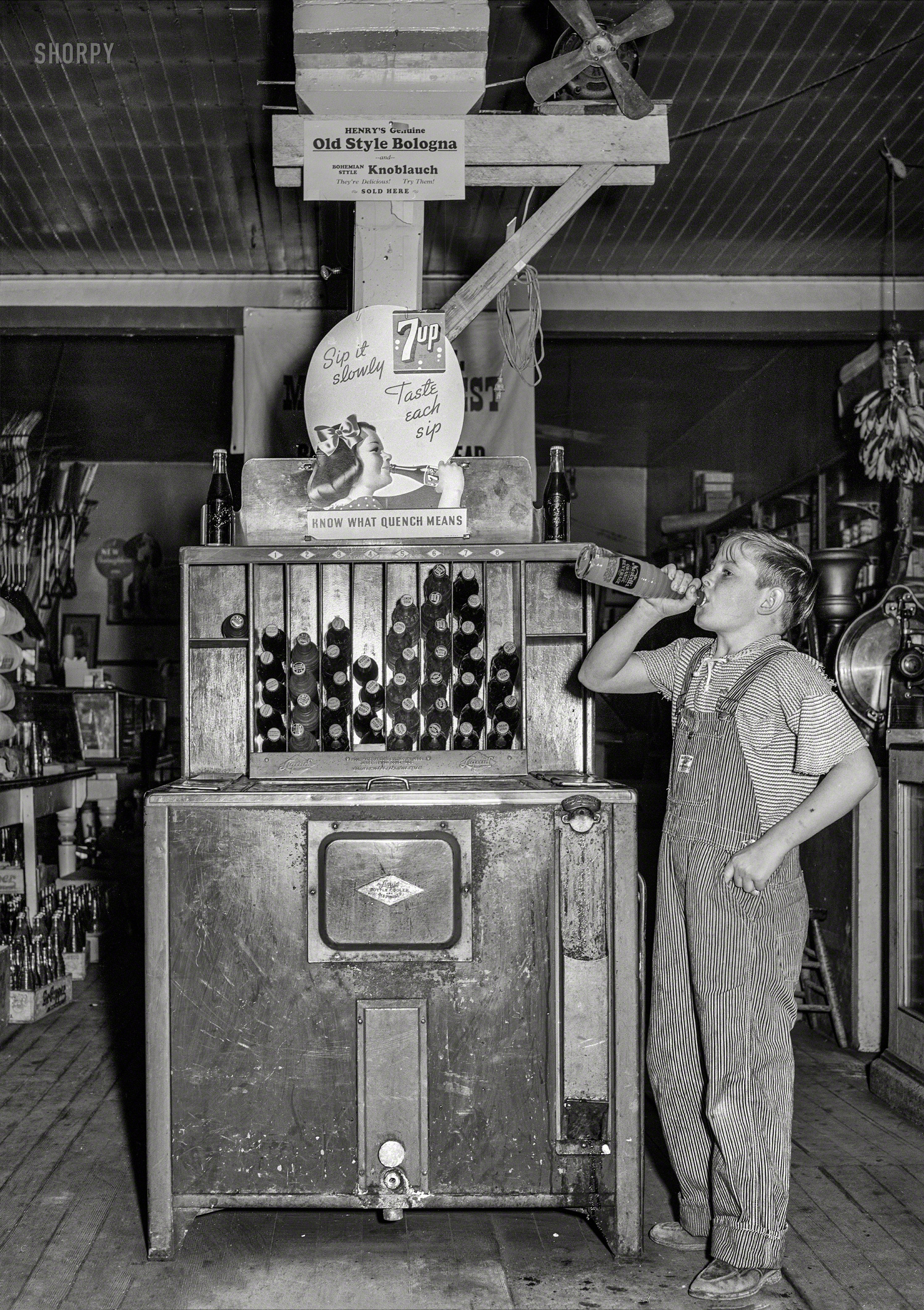October 1939. "Farm boy at pop stand. General store in Lamoille, Iowa." Our young soda-swigger evidently a Nesbitt's man. Medium format acetate negative by Arthur Rothstein for the Farm Security Administration. View full size.