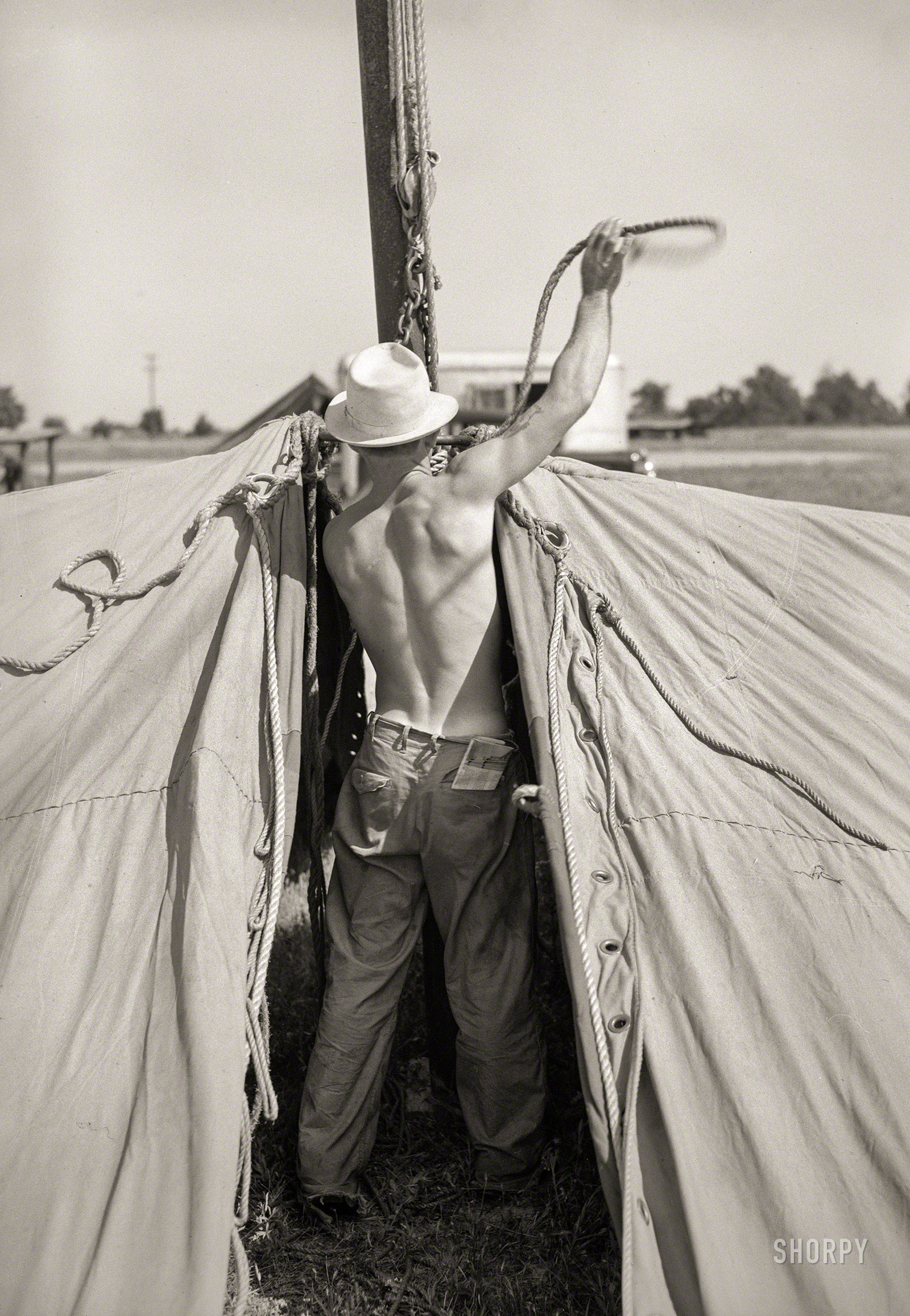May 1938. "Member of carnival crew at work erecting tent for Lasses White traveling show. Sikeston, Missouri." Photo by Russell Lee. View full size.