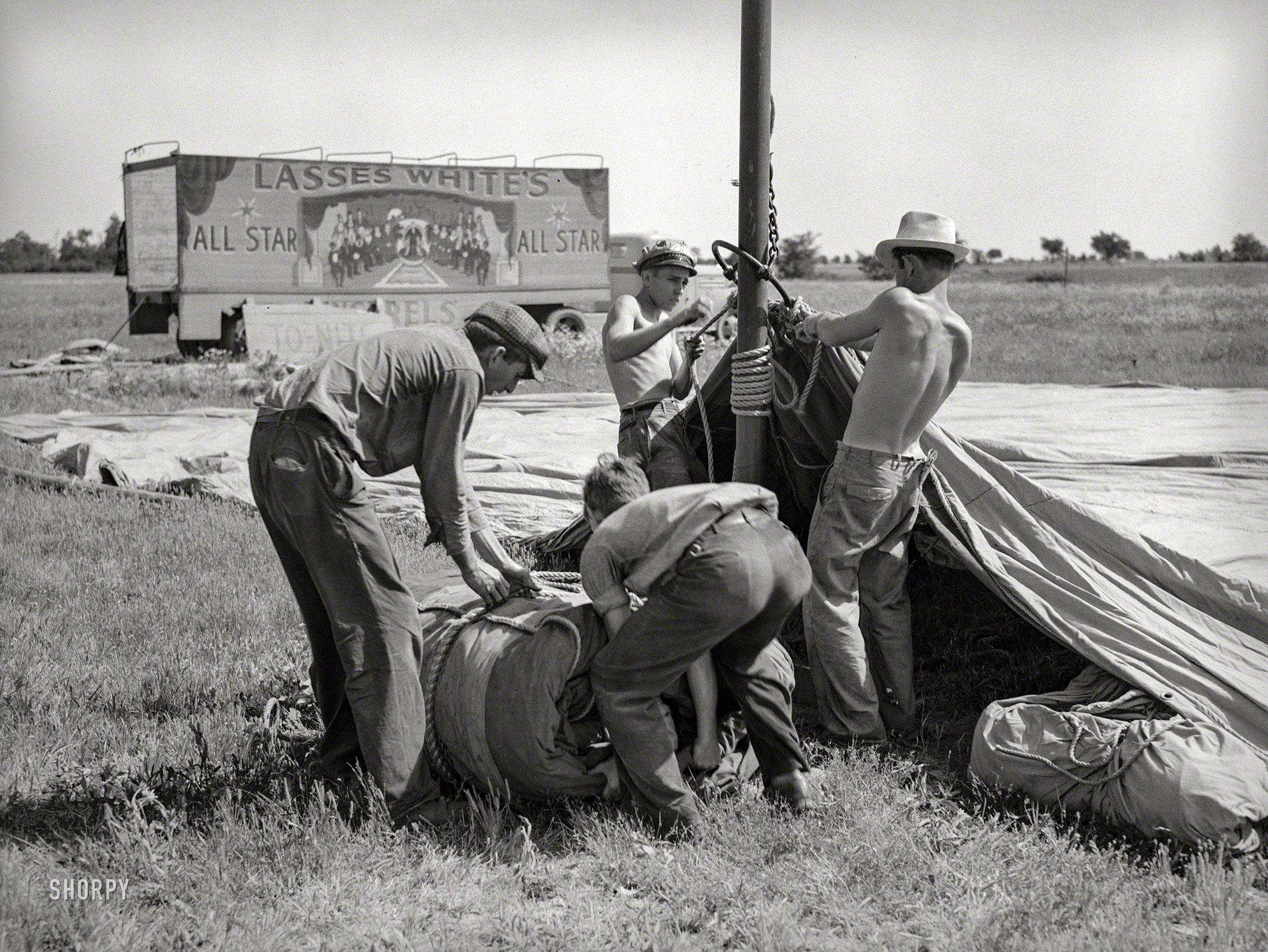 May 1938. Sikeston, Missouri. "Erecting tent for Lasses White show." Lasses being Lee "Molasses" White (1888-1949), minstrel-show impresario as well as star of radio, stage and screen in the first half of the last century. Acetate negative by Russell Lee for the Farm Security Administration. View full size.