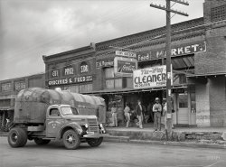 April 1939. "Wholesale truck in front of grocery store. San Augustine, Texas." Photo by Russell Lee for the Farm Security Administration. View full size.
Smilin&#039; Ralph YarboroughRalph Yarborough ran for Texas Attorney General in 1938, but finished in 3rd place. He eventually, however, became a United States Senator for Texas from 1957 to 1972. On November 22, 1963, he was in the second car in the motorcade rather than with President Kennedy, as he and John Connally were not on friendly terms. 
He was an old fashioned Texas liberal, seventh child of eleven, and given to such sentiments as "Let's put the jam on the lower shelf so the little people can reach it." 
J. Frank Dobie called Yarborough "perhaps the best-read man that Texas has ever sent to Washington" (let's not get into any heated discussions concerning the state of literacy in the State of Texas).
Points of InterestThe tractor is a 1939 International Model D-30. There are at least 11 patches in the trailer roof. There is a hole in the grille for a hand crank. Doubt if it was ever used. The driver had to disconnect his air brake lines to be able to jackknife the truck into the loading dock.  Air brake gladhands (airline connectors) and electrical plug are normally mounted in the three holes on the front of the trailer frame. I wonder why they were moved? I’m guessing the metal box behind the spare tire is actually some kind of tank.
Still Cleaning!Looks like the Nu-Way storefront still houses a cleaners. At least it did in Oct. 2013, when this Google Street View was taken. 
STU-The other telephone pole candidate is Robert Alda "Bob" Stuart, a former state senator and Fort Worth wheeler-dealer who ran for railroad commissioner in the 1938 Democratic primary.  He finished fourth.  In the same primary W. Lee "Pappy" O'Daniel was effectively elected governor.   
Little Guys?Who are the little guys in the cleaner's window?
(The Gallery, Cars, Trucks, Buses, Russell Lee, Stores & Markets)