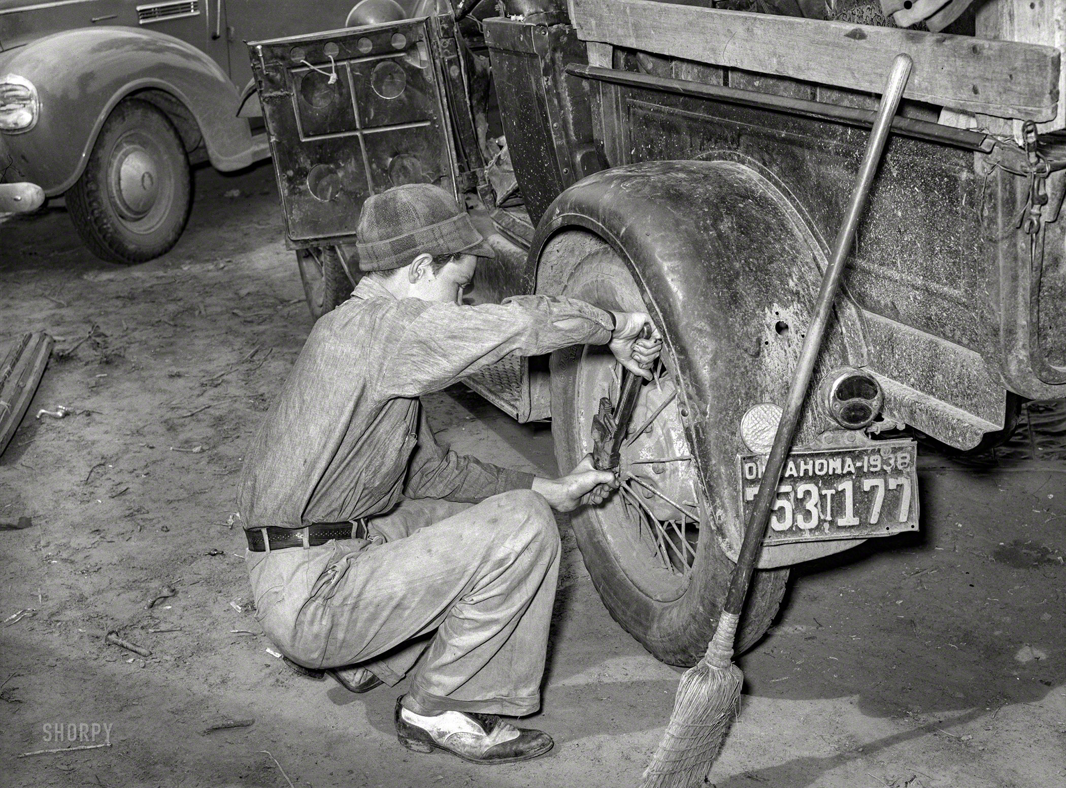July 1939. "Migrant boy who is somewhat of a mechanic tightening the rear wheel on truck which will carry his family [that of of tenant farmer Elmer Thomas] to California from Muskogee, Oklahoma." Photo by Russell Lee. View full size.