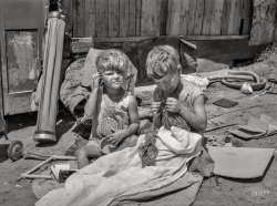 July 1939. "Children of May Avenue camp, Oklahoma City. Their father is a trasher and they are playing with some things he picked up." Medium format negative by Russell Lee for the Farm Security Administration. View full size.