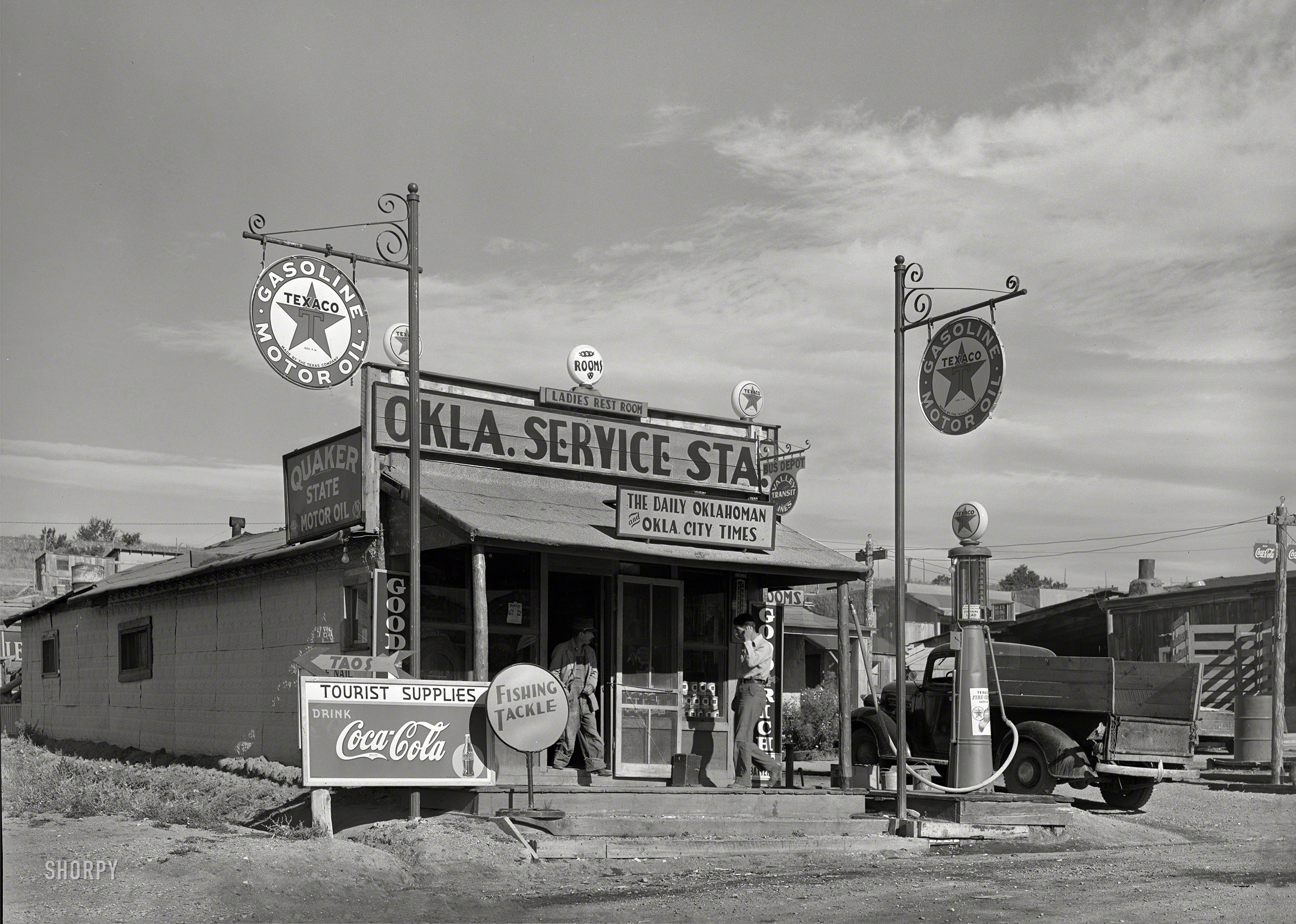 September 1939. "Service station run by former resident of Oklahoma in Questa, New Mexico. Oklahoma newspapers as well as other Oklahoma products are for sale here." Photo by Russell Lee for the Farm Security Admin. View full size.