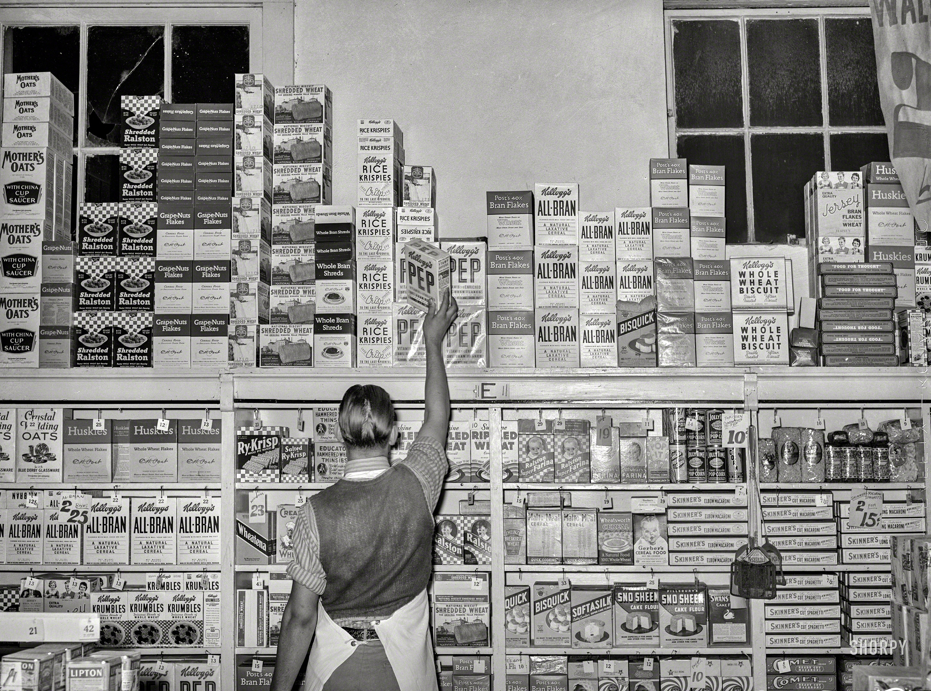 November 1939. "Placing packaged goods on display rack. Retail grocery in San Angelo, Texas." Medium format negative by Russell Lee. View full size.