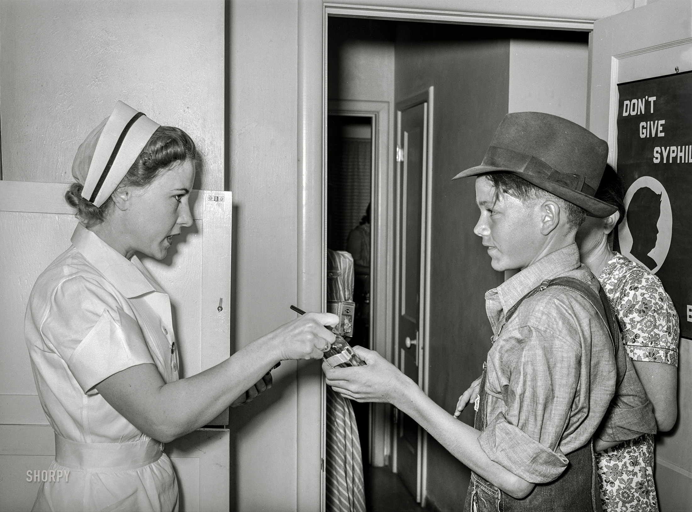 May 1940. "Nurse giving instructions to son of migratory laborer as to how to take medicine. Agua Fria migratory labor camp, Arizona." Acetate negative by Russell Lee. View full size.
