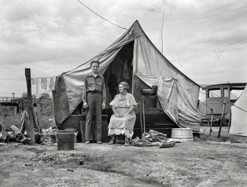 November 1936. "Squatter camp on the flat where families live during the orange picking season near Porterville. Part of migrant family of five, native Californians, waiting for work in the groves." Photo by Dorothea Lange for the Farm Security Administration. View full size.
