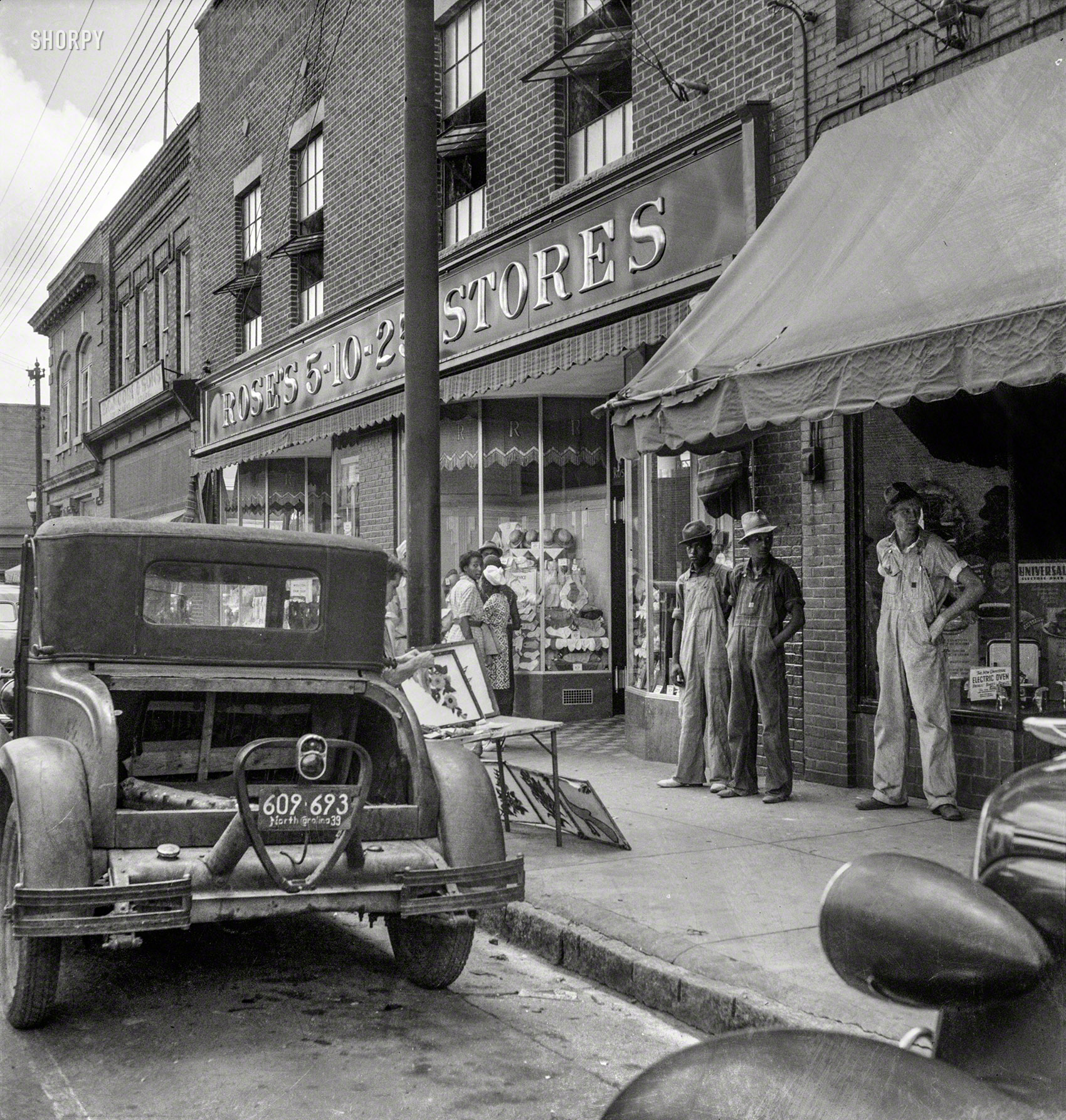 July 1939. "Appliqued embroideries for sale on street in front of ten cent store. Saturday afternoon. Siler City, North Carolina." Medium format negative by Dorothea Lange for the Farm Security Administration. View full size.