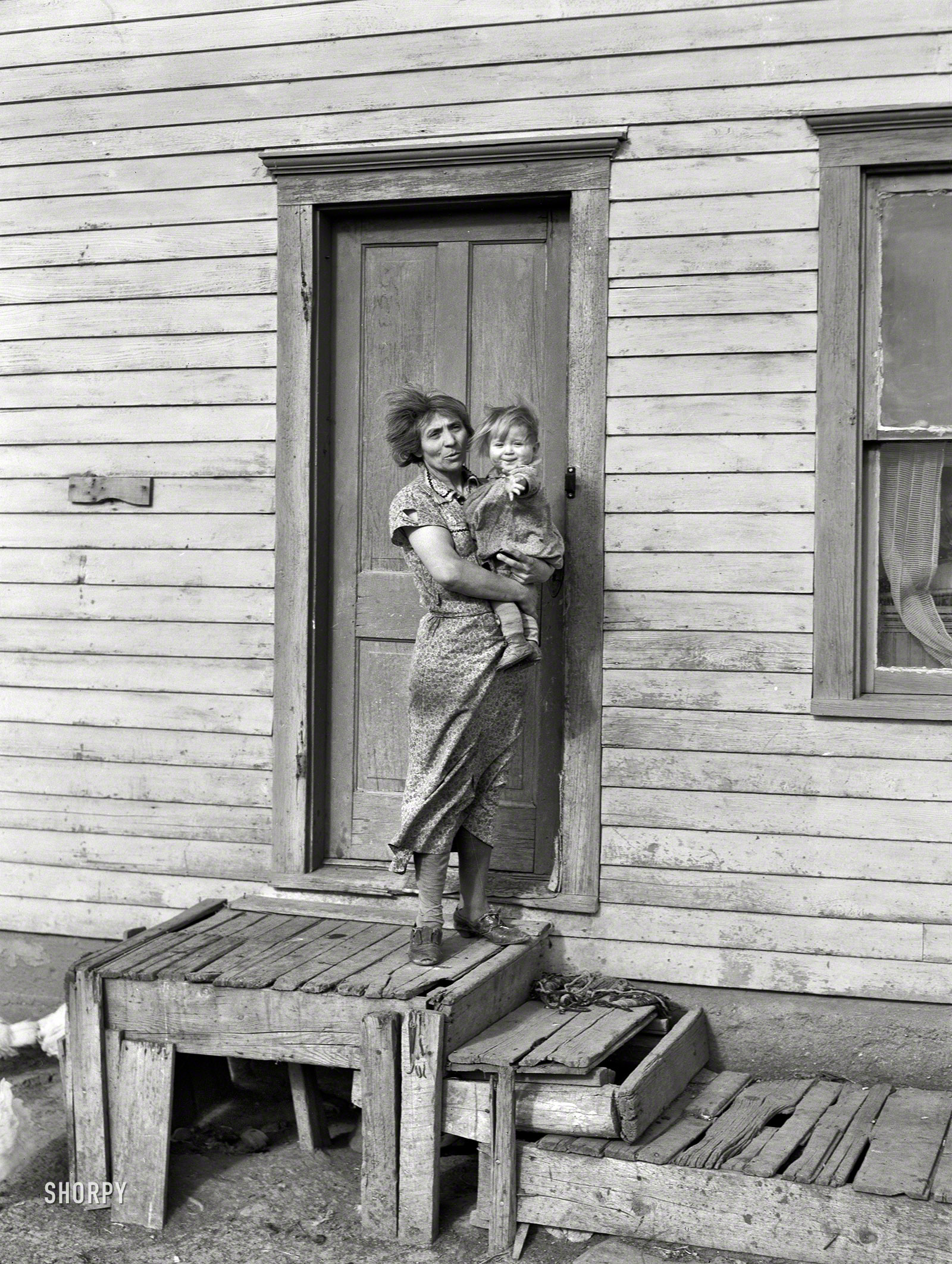 November 1937. "Mrs. John Baker and baby on steps of farm home. Divide County, North Dakota." Photo by Russell Lee for the FSA. View full size.