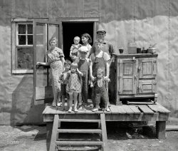 &nbsp; &nbsp; &nbsp; &nbsp; Black River Falls (vicinity), Wisconsin. April-June 1937. Photographs show families who live on small farms in cut-over areas. Dilapidated log cabins and shacks; interior details. Poor families; Bohemian farm families. Few scenes in town.
June 1937. "Ray Allen family near Black River Falls, Wisconsin." Medium format negative by Russell Lee for the Resettlement Administration. View full size.
Bug ScreensDuring the depression bug screens were such a precious commodity that people used to tether their dog to the front door to make sure nobody would steal it while they were away and that wild animals couldn't tear it. They didn't have HVAC in those days and the houses were often improperly shaded so the kitchen could make the heat unbearable in the summer and open windows and doors would bring in bugs. This house has screen doors without any tears and this couple has obviously kept their children bathed and kempt under very difficult circumstances.
Seven kids!Oldest daughter looks about 13, Mom &amp; Dad look like they might be 30.
Mom looks mighty proud of her brood!
Good-lookin&#039; mobI say, if all those children are that lady's, then I would say she has weathered the years well. They all look healthy and I hope life improved for them. I also hope there was a lot of love in that family.
(The Gallery, Kids, Russell Lee)