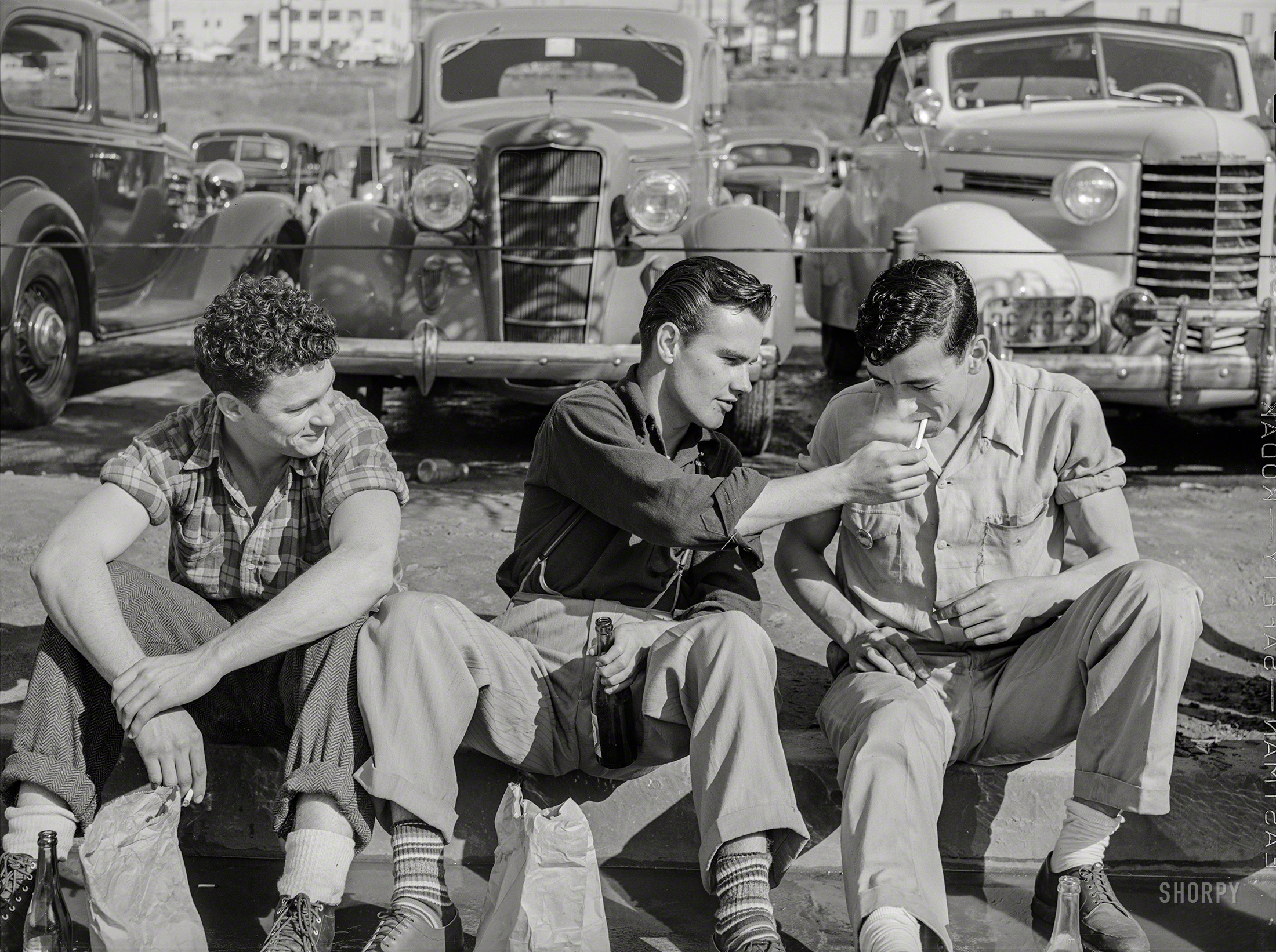 December 1940. "Workmen during lunch period, across the street from the Consolidated Aircraft factory. San Diego, California." Medium format negative by Russell Lee for the Farm Security Administration. View full size.