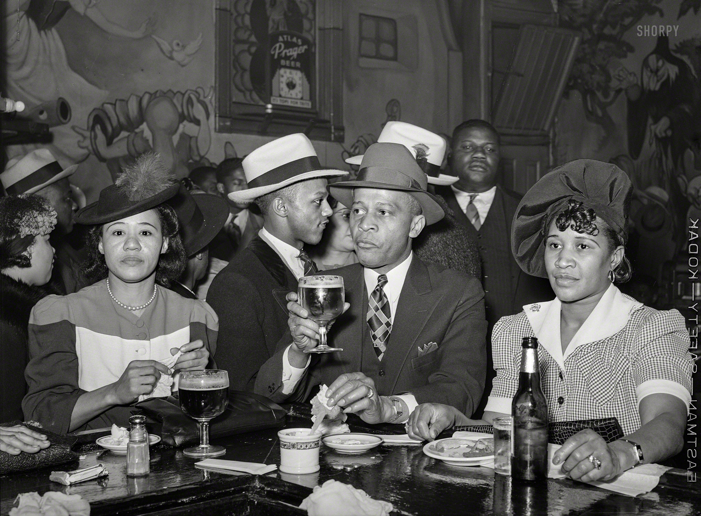 April 1941. "South Side Chicago. Scene in Negro tavern." The walls adorned with murals from the Disney version of "Snow White." Medium format negative by Russell Lee for the Farm Security Administration. View full size.