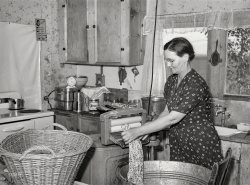 May 1941. "Mrs. E.E. Botner, wife of FSA rehabilitation borrower, wringing laundry in electric wringer. This family has been on the project for about five years. Vale-Owyhee irrigation project, Malheur County, Oregon." Medium format negative by Russell Lee for the Farm Security Administration. View full size.