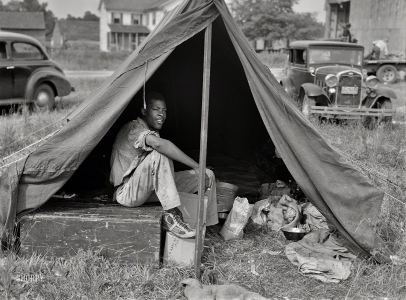 July 1940. "Florida agricultural migrant with a group who had their own tent which they pitched outside the grading station at Belcross, North Carolina." Photo by Jack Delano for the Farm Security Administration. View full size.
