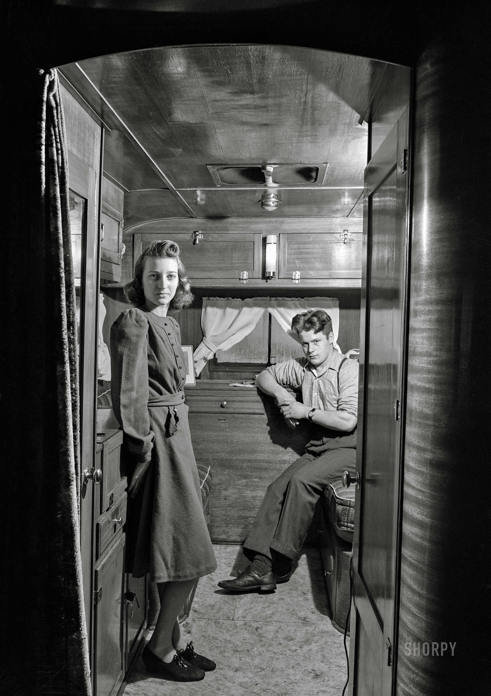 December 1940. "War boom in a New England industrial town. Mr. and Mrs. Leslie Bryant in their trailer about two miles out of Bath, Maine. Mr. Bryant works in the shipyard. They have been living in the trailer for two months. They could not rent in Bath and although a trailer cost them almost as much as a house, Mr. Bryant feels that it is a better investment because they do not know where they will go next in search of work when this 'boom' is over." Medium format acetate negative by Jack Delano for the Farm Security Administration. View full size.
