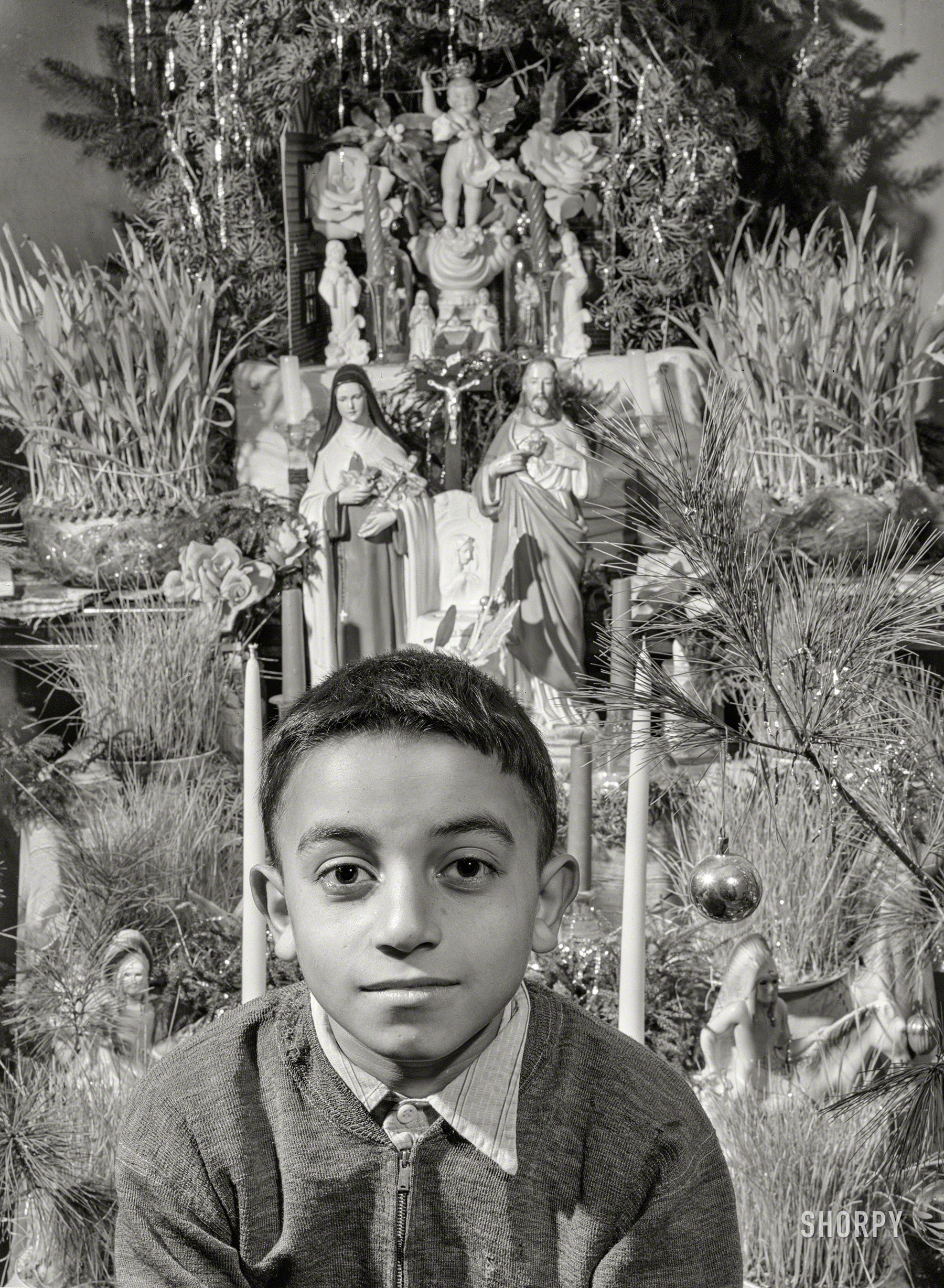 December 1940. "Manuel Andrews, a Portuguese boy near Falmouth, Massachusetts. Family runs a seven-acre vegetable farm and have one 'new' cow of which they are all very proud. Father is a laborer in an Army camp nearby. Shot was taken just after Christmas." The tree decorated with ceramic figures of Mary, Joseph and Geronimo. Acetate negative by Jack Delano. View full size.