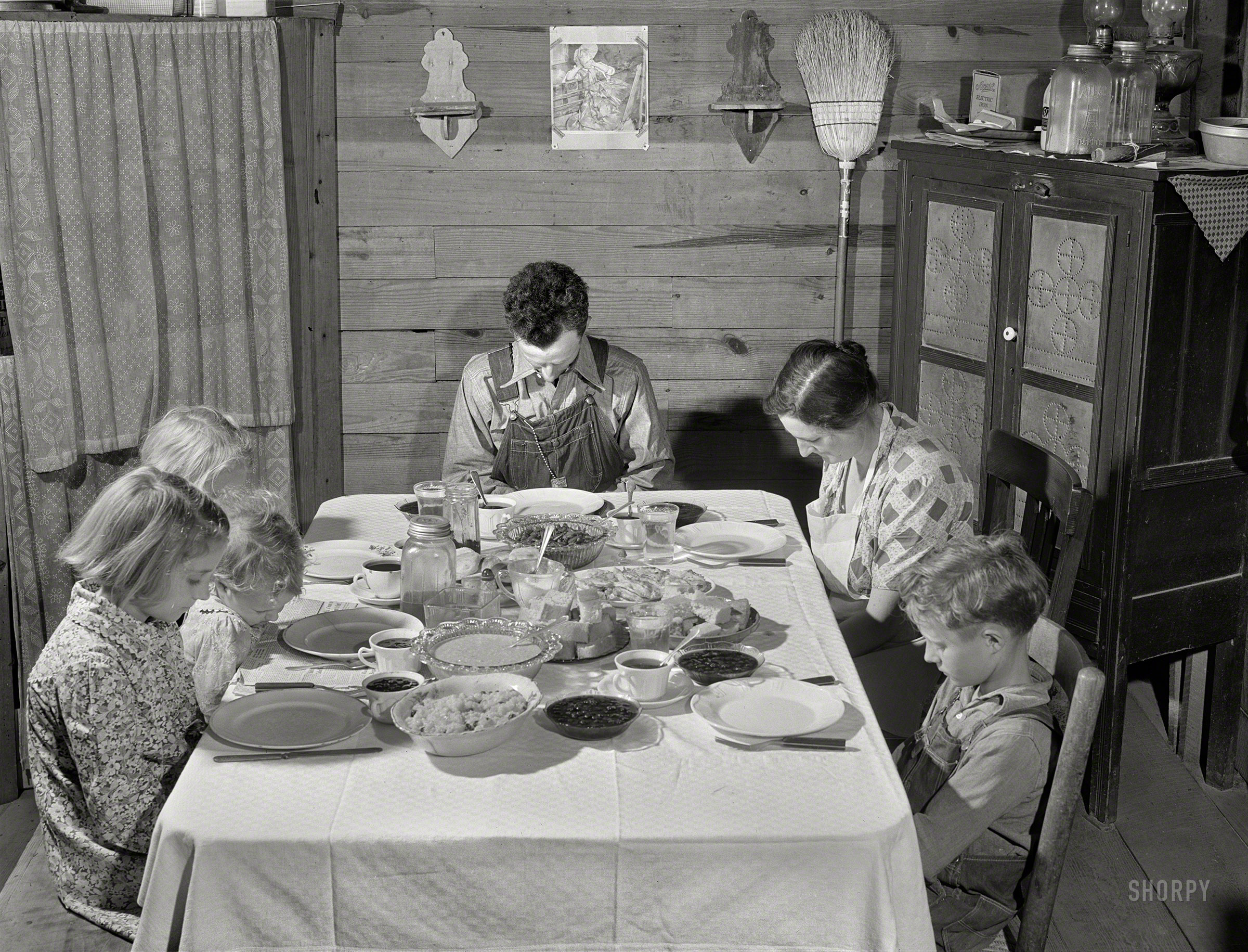 April 1941. "Family of Lemuel Smith, Farm Security Administration borrower, saying grace at the afternoon meal. Carroll County, Georgia." Medium format acetate negative by Jack Delano for the FSA. View full size.