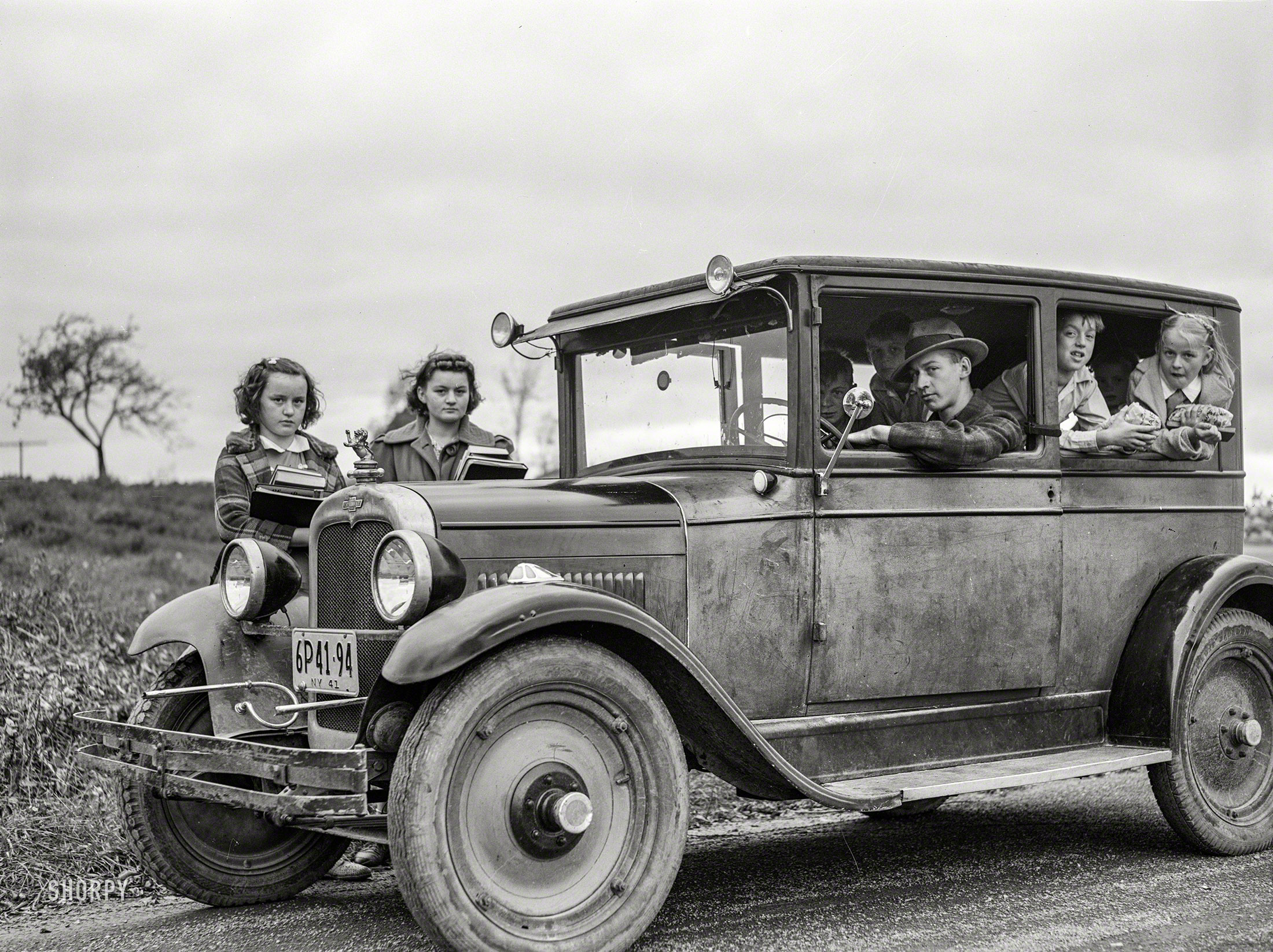 October 1941. "Children of Dan Sampson, who moved out of the Pine Camp expansion area in August, waiting in the family car for the school bus near South Rutland, New York." Medium format negative by Jack Delano. View full size.