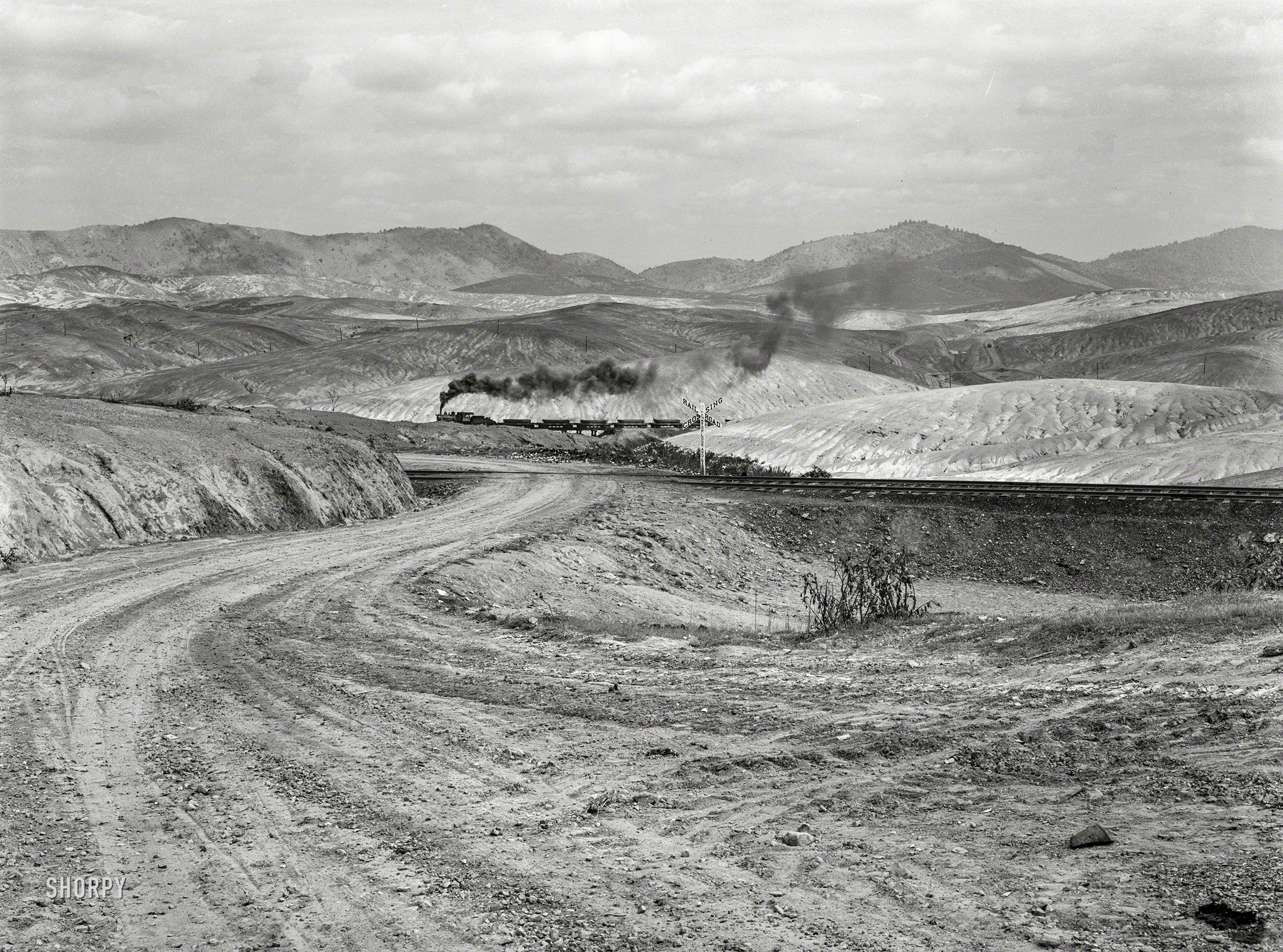September 1939. "Ducktown, Tennessee. Train bringing copper ore out of mine. Fumes from smelting copper for sulfuric acid have destroyed all vegetation and eroded the land." Medium format negative by Marion Post Wolcott for the Farm Security Administration. View full size.