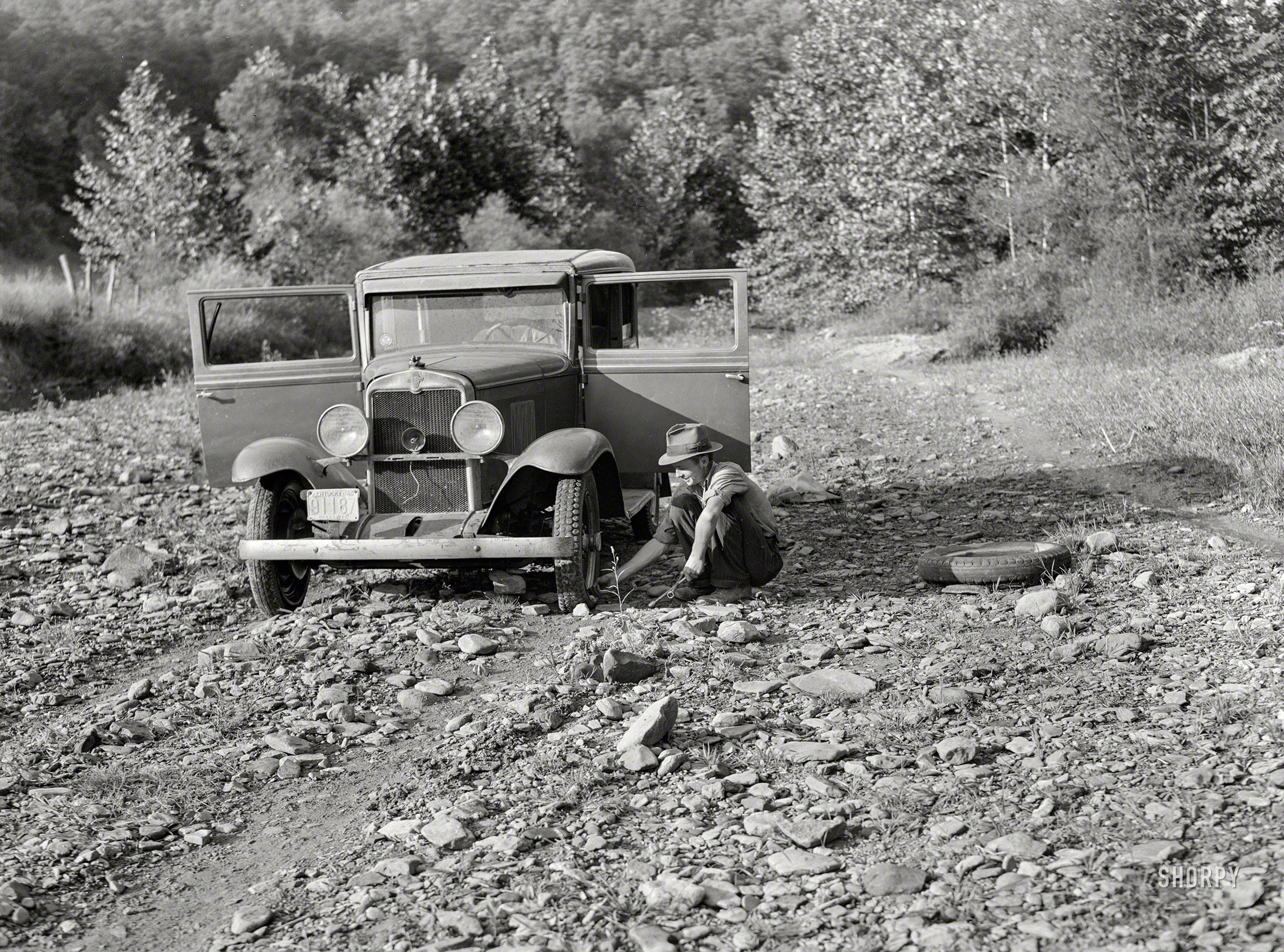September 1940. "Breathitt County school superintendent changing tire in streambed. South Fork of Kentucky River." The "Double Cola" Chevy seen earlier here and here. Photo by Marion Post Wolcott, who is probably not getting any more rides with this fellow. View full size.