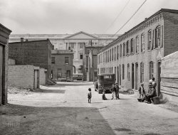 &nbsp; &nbsp; &nbsp; &nbsp; A scene last glimpsed here, but without the trolley.
September 1941. Washington, D.C. "Schoots Court [i.e., Schott's Alley] with Senate Office Building in background. Four very small dark rooms rent for fifteen and eighteen dollars per month with water and privy in yard. It used to rent for six and eight dollars. Frank Coles and his friend are sitting on the bench. He was a cement plasterer but has been on relief during the past year. He has frequent heart attacks and his feet and ankles are all swollen. Doctor advises a chicken and lamb diet, no pork or beef, but he doesn't even have money to buy fuel. He can't get waited on in a clinic or get to one. He waited from before 11 until 4 p.m. but still could not see a doctor. He has been in Washington since 1906." Medium format acetate negative by Marion Post Wolcott for the Farm Security Administration. View full size.