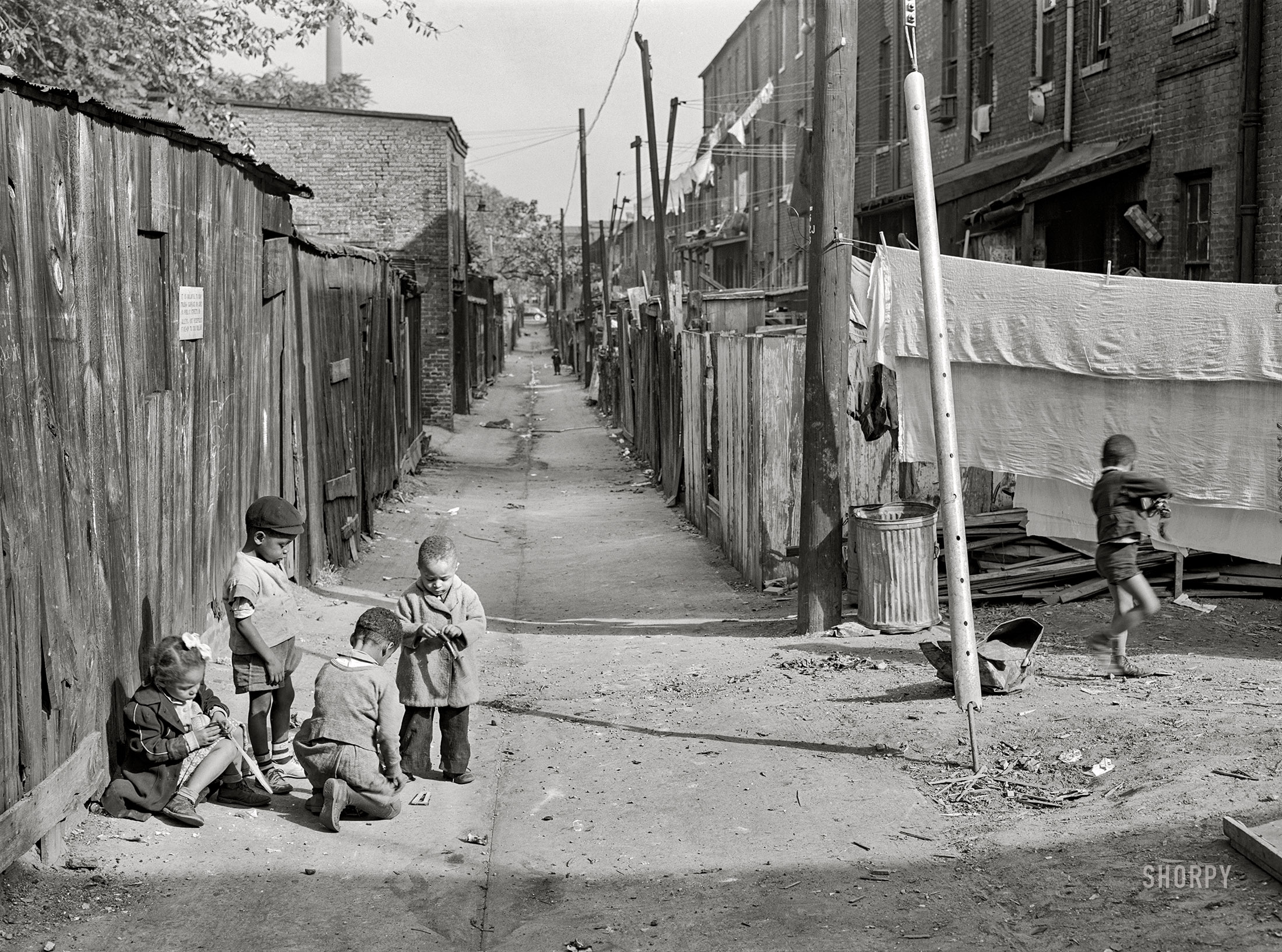 September 1941. "Children playing in DeFrees Alley, N.E. Washington, D.C., near Capitol building. One basement room rents for nine dollars a month; two rooms upstairs for sixteen dollars; one bath and cold water in the hall for entire building." Medium format acetate negative by Marion Post Wolcott for the Farm Security Administration. View full size.