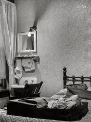 June 1939. "Hotel bedroom. Elkins, West Virginia." The Bare Bulb Arms hopes you enjoy your stay in the Edward Hopper Suite. Acetate negative by John Vachon. View full size.
Vachon knew what he was doingMust be another bulb on the room's ceiling -- or maybe it's a nice combination of flash and available light.
Just comfortingI know the hotel may have been something of a "flophouse", and you might have been able to hear your neighbors and smell every cigarette ever smoked in the hotel, but there is something comforting about those old rooms with wallpaper, decent millwork around the windows and doors, and a very basic bed.  Takes me back to many happy days in the homes of my grandparents.
The Name should be Bare Bones InnWhat do you want to bet that is only one room and every room in the inn is like that.  This was before the days of luxury suites we have now.
LOL!!!!Edward Hopper Suite!! I'm rolling around on the carpet. Love this place!
Welcome to the Hotel NoirFree electric lighting and hand towels included in room rate. Modern water closet facilities conveniently located on every floor! Hotel bath and wash room available (25¢).
Speaking of aromasIt was not entirely unknown for men of a certain height to use the sink for other purposes, especially on cold nights when a trek down the hall seemed particularly daunting.
We&#039;ll leave a light on for you.Probably was a welcome sight after a day of driving the roads back then.
No TV but if you're lucky you can watch the bedbugs and cockroaches fight.
Whose Room?Considering the intimate nature of the image, wonder if Mr. Vachon is the one doing the unpacking.
Elkins!I lived there from 1967 to 1972.  Great little town, and home to the annual Mountain State Forest Festival which was held earlier this month (October).
(The Gallery, John Vachon)