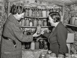 November 1940. "Home supervisor examining canned goods of FSA rehabilitation borrower in food storage cave. Labette County, Kansas." Acetate negative by John Vachon. View full size.