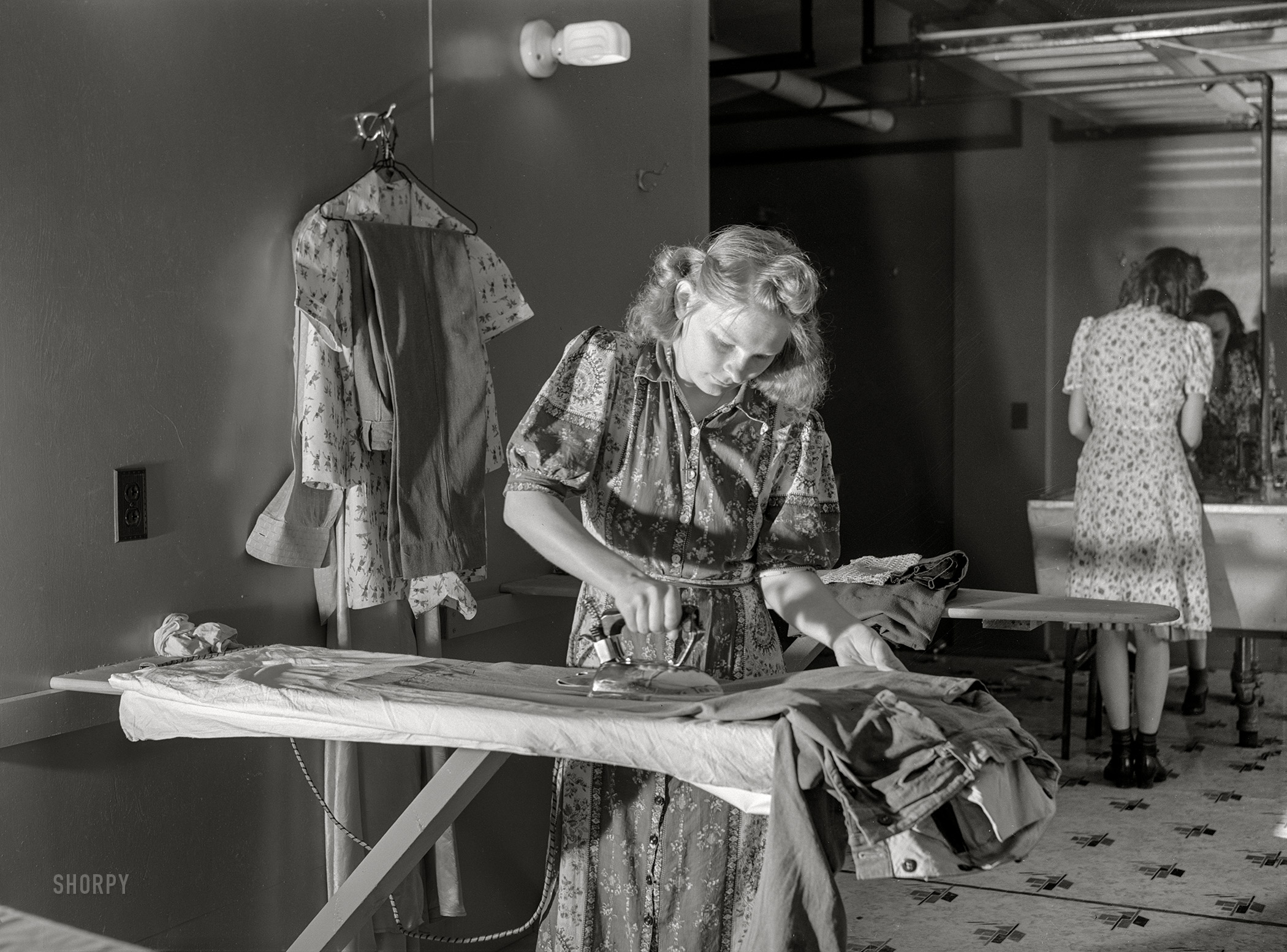 June 1941. "Wife of defense worker ironing clothes in utility building at FSA trailer camp. Erie, Pennsylvania." Photo by John Vachon for the Farm Security Administration. View full size.