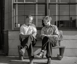 August 1941. "Sunday afternoon. Farm boys in front of beer parlor in the Finnish community of Bruce Crossing, Michigan." Medium format acetate negative by John Vachon. View full size.
Since I&#039;m not that oldI have a question about styles back then. Was rolling one's socks down a fashion "thing" back then?
Socks May Have Been Different ThenI can't speak to '40s fashion trends, but as a boy in the 1960s, my socks only had elastic in the very tops.  The elastic was very brittle and would break after a few washings.  Then my socks would slide down like the guy on the right.  My socks never stayed up well until the infamous knee-high striped tube socks of the '70s.
Up Your HoseNo men's sock of the 1940s would stay up for long. So, rolling it down over a finger twist made a tight roll that would stay up. Otherwise, it was sock garters or socks disappearing down into the heels of your shoes.
Droopy socksI am a little older, so I know about the sock conundrum. The elastic in socks in those days only lasted a few washings. My grandfather wore something called “galluses” that were like a garter belt for the socks. The galluses were worn above the calf and had suspenders that attached to the top of the sock, holding them up. The other solution to droopy socks was to twist the loose material into kind of a bunch, then roll the sock down over it, which is probably what the guy on the right has done. If you did nothing at all and let the socks droop, they would crawl down into your shoes after a period of time, which would require you to take off your shoes, pull the socks back up and start again.
Common European &#039;thing&#039;My father-in-law was a Czech immigrant (1950), and recently passed at the age of 97. He kept to most of his homeland's traditions, including Czech foods, music and language in his home. He nearly always rolled his socks down this way, even with modern socks (and sound elastic). Given these young men are likely native Finns, I suspect rolling down one's socks is just a European thing. 
Sock pioneerI think his rolled-down sock style was for comfort in the heat. He may have inadvertently invented the low-rise sock. 
CheershThese two (Sven &amp; Ollie?) looked familiar to me. Back on Feb 29, 2020 they had been tipping a few. This pic appears to have been taken before they consumed their adult beverages.  https://www.shorpy.com/node/25415
Beer Parlourwas a term I only thought was from Moose Jaw  Saskatchewan where I was from, and the term was appropriate, they were just big rooms with smoke and beer and that was all.
(The Gallery, John Vachon, Small Towns)