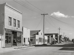 August 1941. "Ewen, Michigan. Former lumber town in Ontonagon County." Medium format acetate negative by John Vachon for the Farm Security Administration. View full size.
Anytown USASadly, a similar scene is playing out across the nation and for good reason. Keep your distance and please stay safe all. Thanks to Shorpy for reminding us and keeping us entertained in time of need.
Not too much left
Masonic light globeMaybe they held their meetings upstairs above the print shop.
Everyman in AnytownIt's nice to see that places like this still exist. These days Anytown USA is made from a cookie cutter, with the same shops, and the same restaurants. 
And way fewer phone linesJudging from the telephone poles the solo stroller is just coming up on what is now Ewen Gas Mart, a British Petroleum station, where they carry only regular and diesel.
He's nicely dressed.  I wonder where he was going?
(The Gallery, John Vachon, Small Towns)