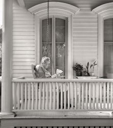 August 1941. "Front porch. Elgin, Illinois." Medium format acetate negative by John Vachon for the Farm Security Administration. View full size.
Enjoying some fresh airWhistler's daughter?
A Long RoadThis lady, surely reading news portending the U.S. entry into WWII, was no doubt born before the Civil War.  She must have taken considerable pride in the fact that she and America had grown up together.
New LensA few years ago, I wouldn't have why she needed that magnifying glass to read a newspaper. Now I know.
New Lens, part 2A few years ago, I wouldn’t have known why some older folks take off their glasses and put the book or newspaper right up close to their eyes to read.  Now I know.
Would love to see the whole houseThe craftsmanship of the windows, the perfectly spaced balusters, the well made and attractive handrail, the tongue and grove wood for the porch floor and the column built with individual curved pieces of wood to form the perfect taper. And then at the bottom edge of the photo we see the perfectly spaced trim to cover the crawl space under the porch. "Craftsmen" of today have  difficult time in drilling well spaced holes to make a crude baluster row and would never even think that the handrail needs to be smooth and have some architectural beauty to it.  
Reducing Her Screen TimeIt's August in Elgin, and I see clips but no screens on those windows.
Kudos to the ownerThat is a very well-maintained home.
Good NewsThis appears to be the same porch and not much has changed!

(The Gallery, John Vachon, Small Towns)