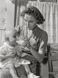 May 1942. "Lancaster County, Nebraska. Mrs. Pierce, wife of FSA borrower, giving her daughter a glass of milk." Photo by John Vachon for the Farm Security Administration. View full size.